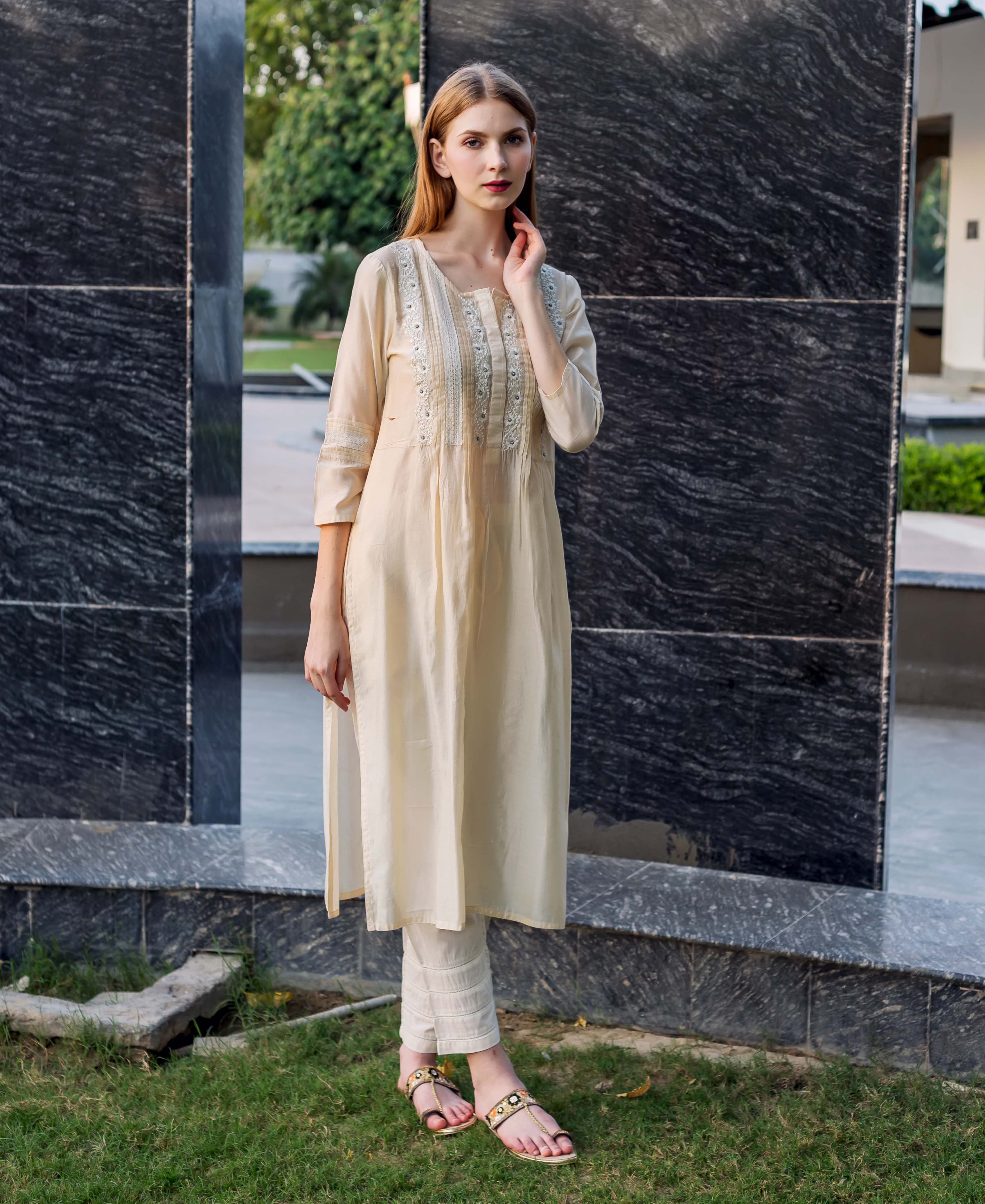 Full shot of model wearing off-white straight embroidered kurta with pintuck and lace details.
