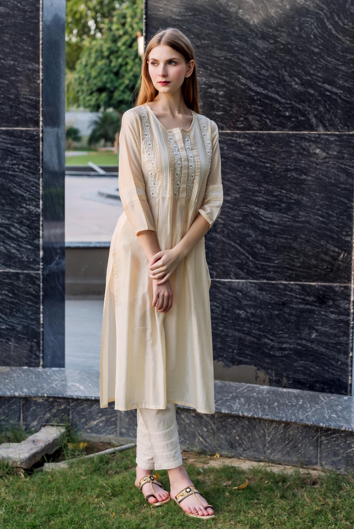 Off-white straight kurta with embroidery, pintucks, and lace details, shown on a model.