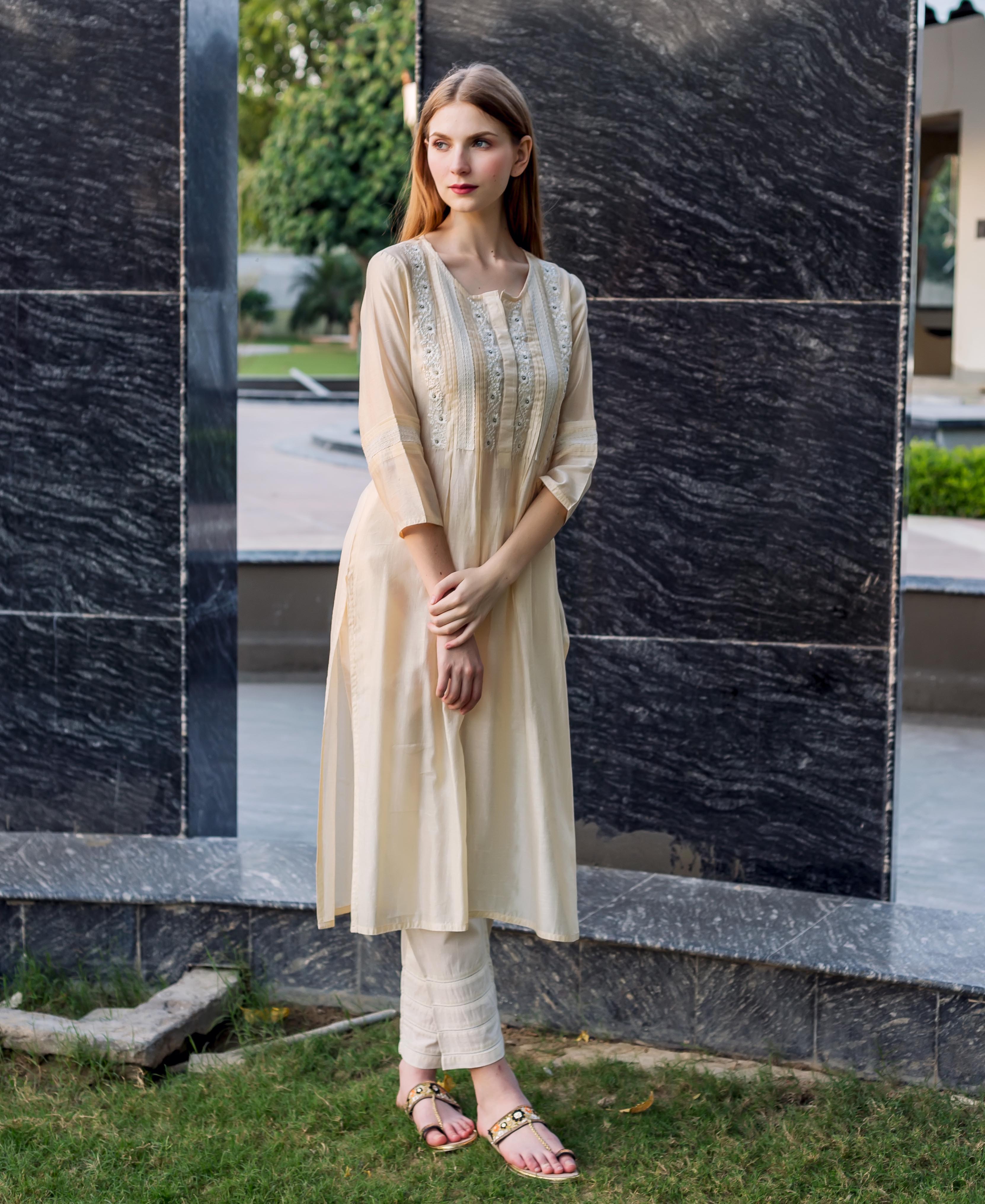 Off-white straight kurta with embroidery, pintucks, and lace details, shown on a model.