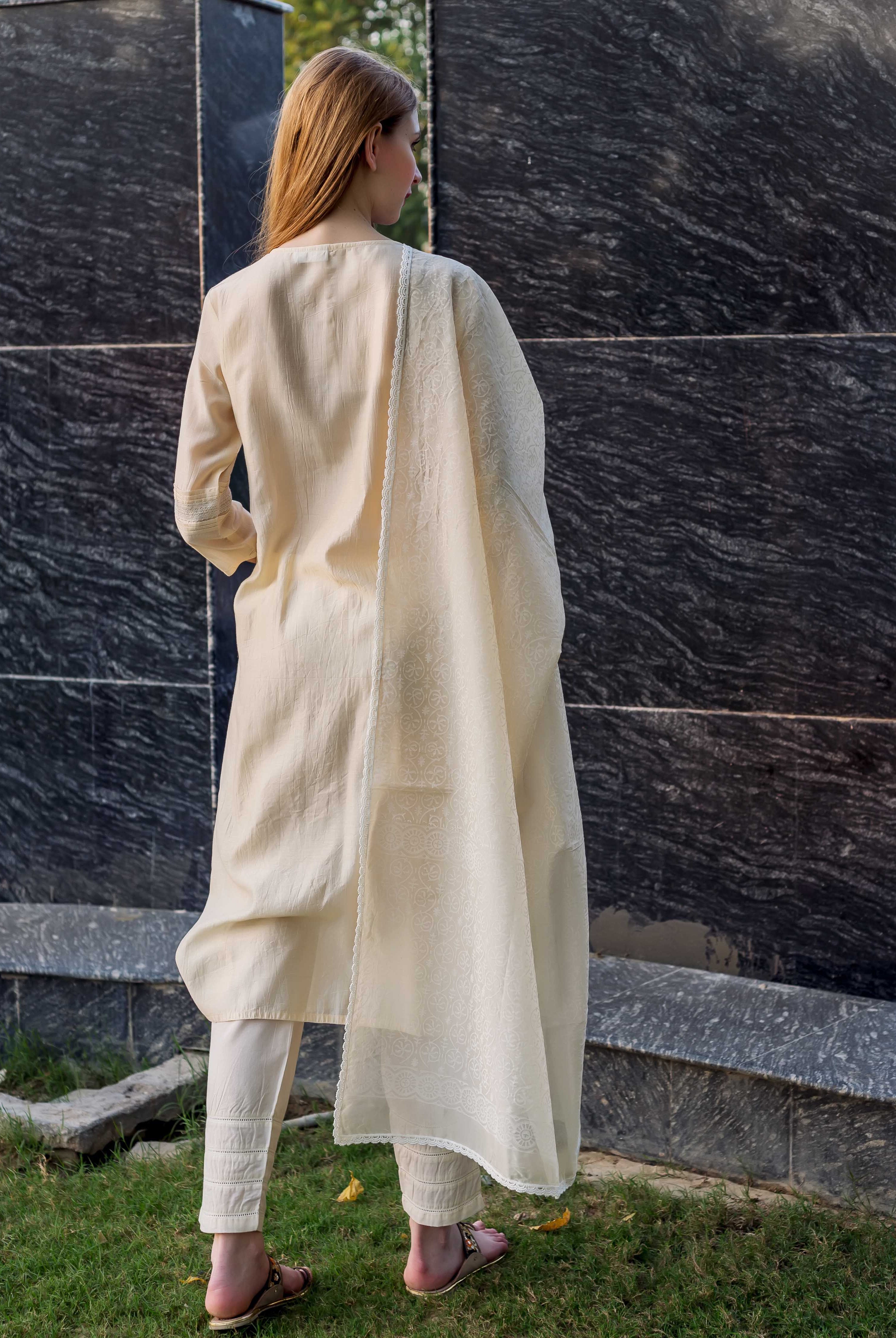 Back view: model in off-white embroidered kurta set, featuring pintuck pants and lace.