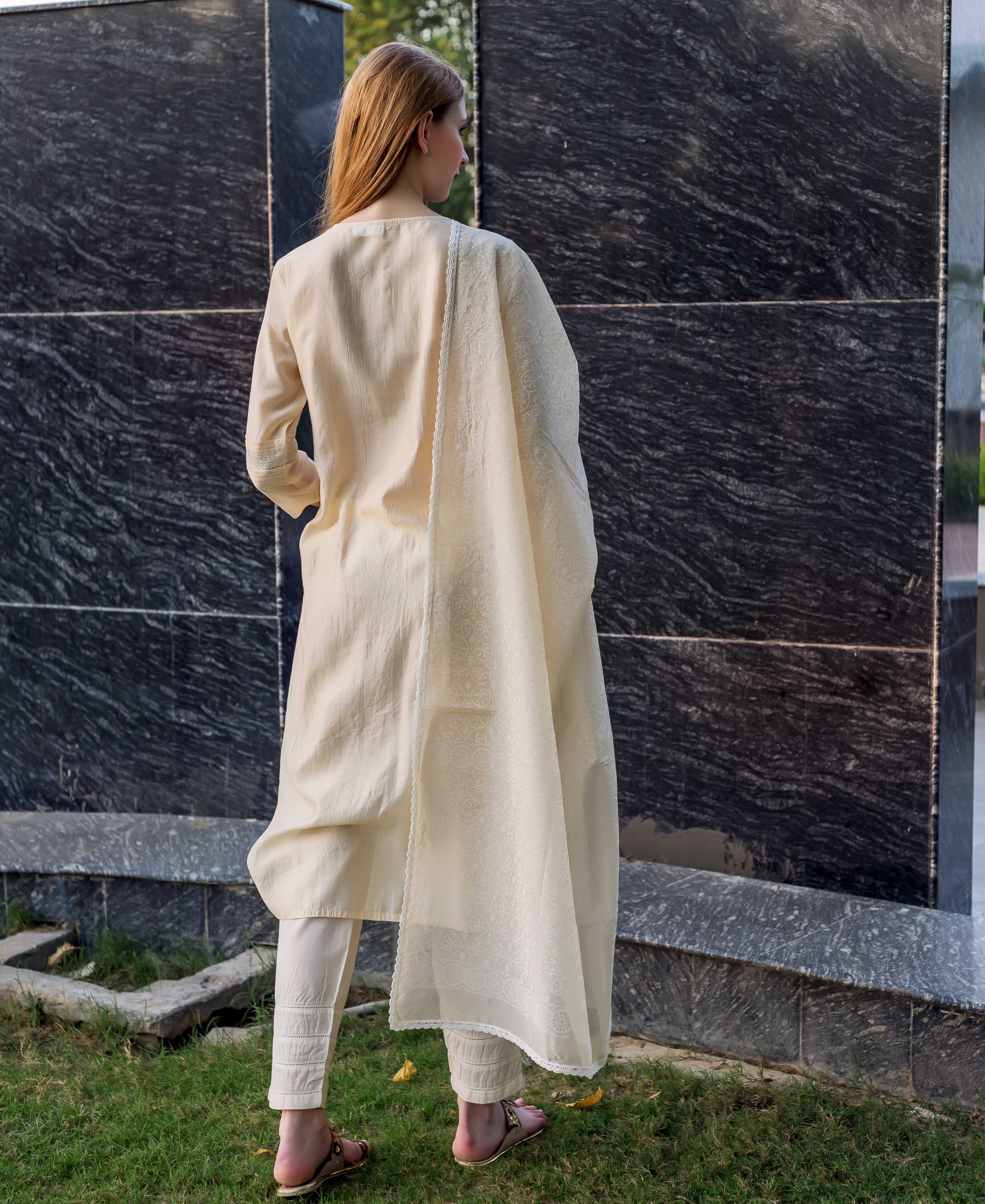 Back view: model in off-white embroidered kurta set, featuring pintuck pants and lace.