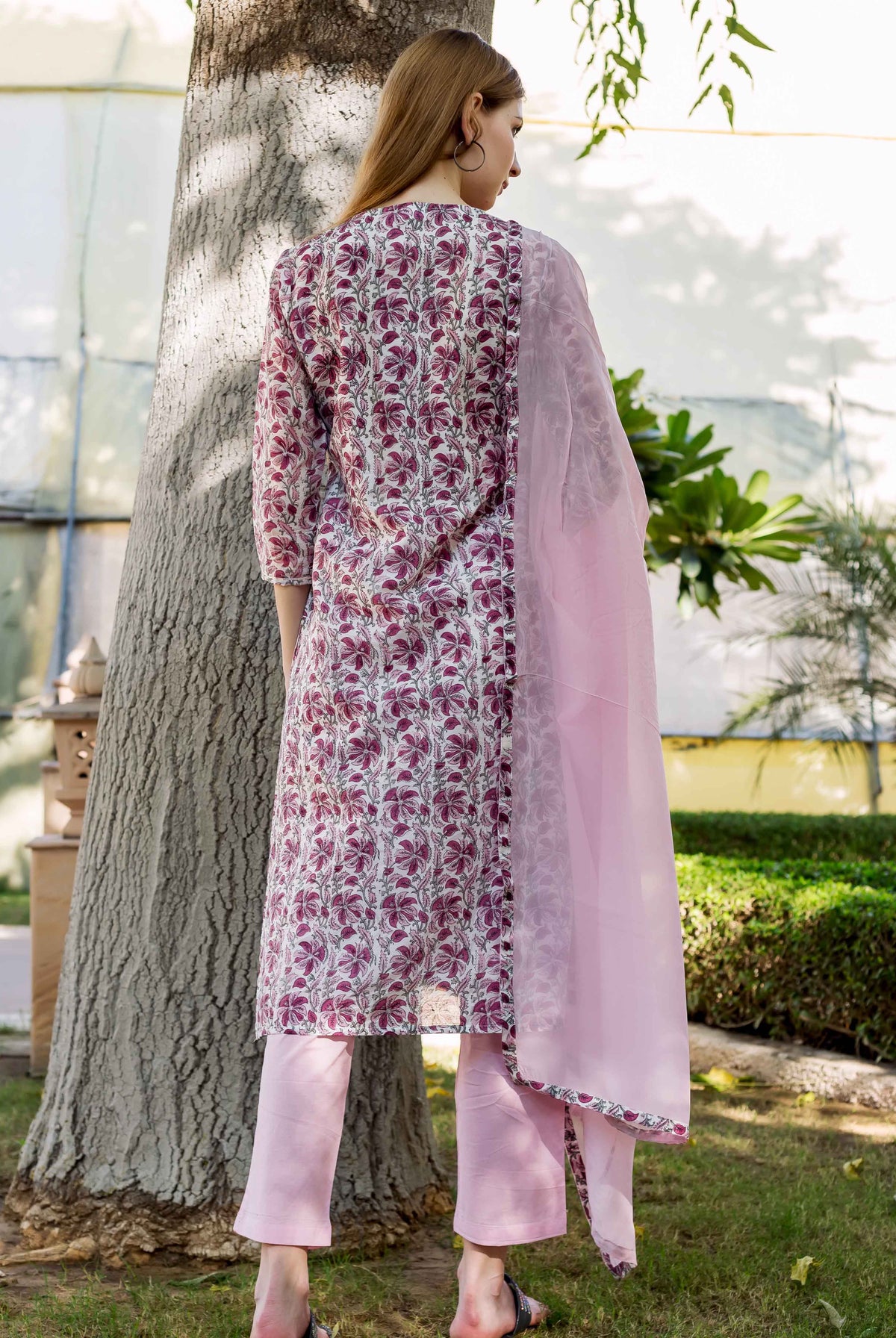Back view of model in a pink and white floral block-printed kurta set with dupatta.