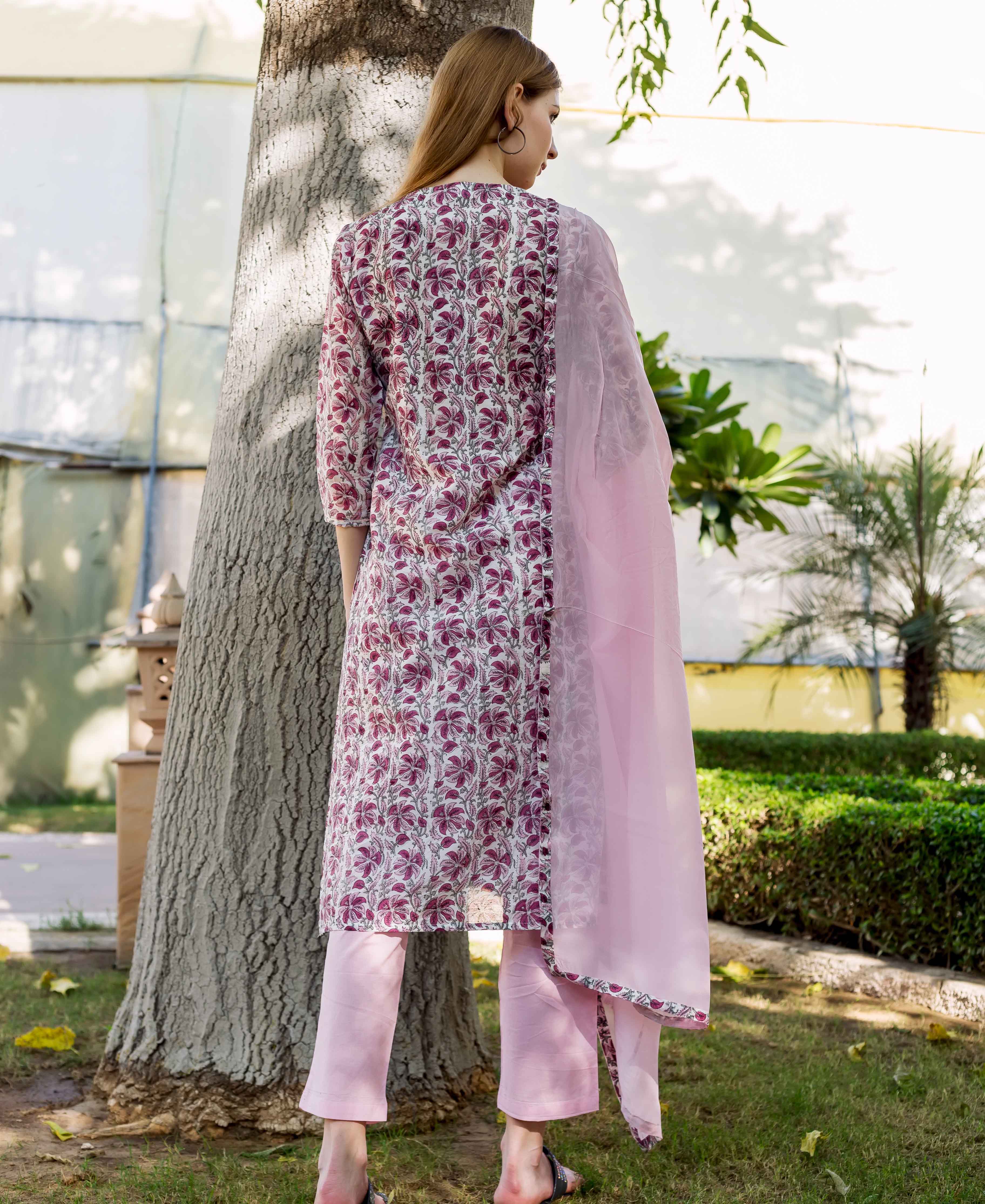 Back view of model in a pink and white floral block-printed kurta set with dupatta.