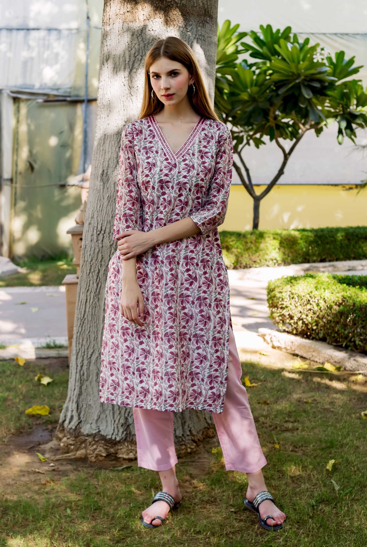 Full-length model in a white and maroon floral block-printed V-neck kurta and pink pants.