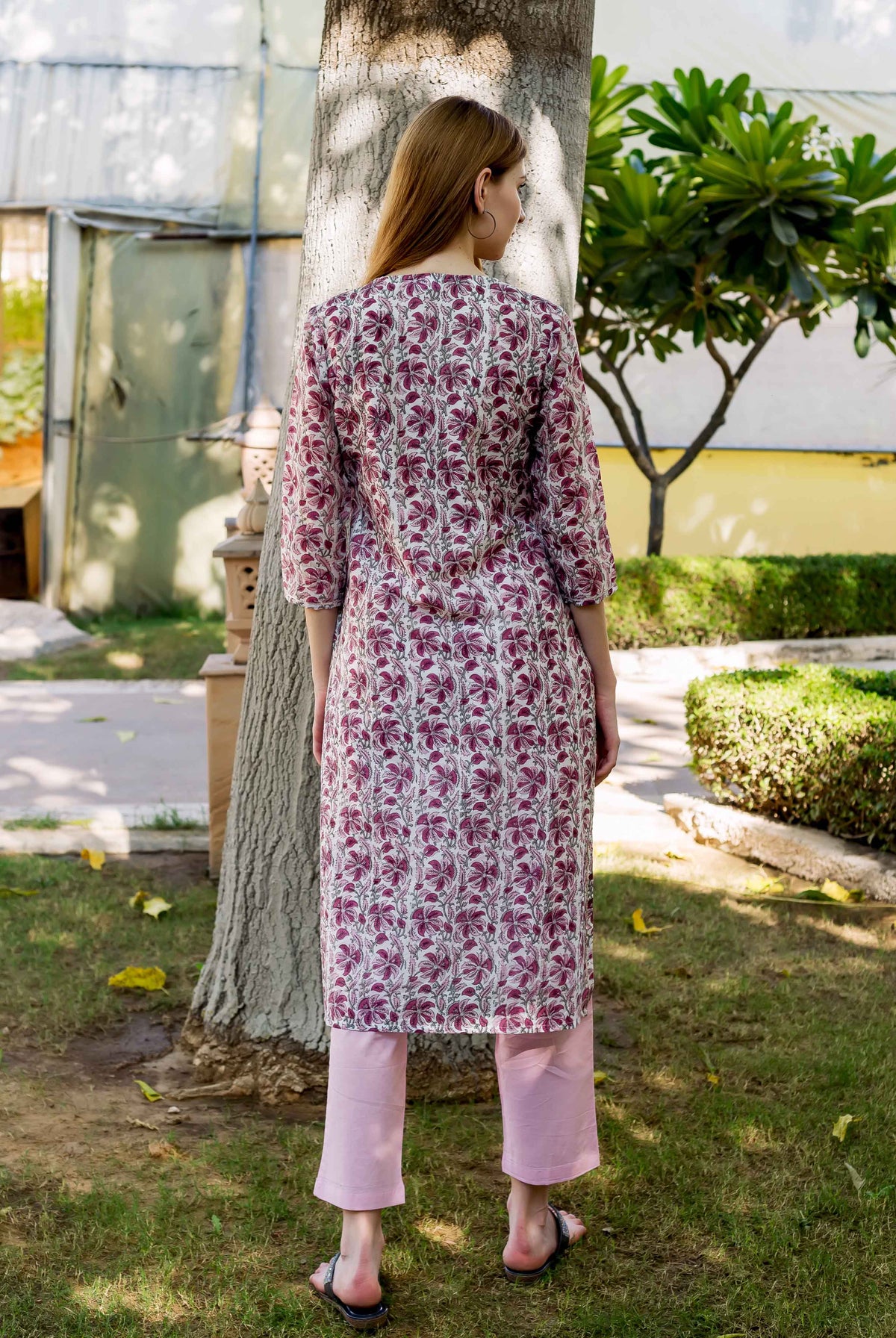 Back view of model in a hand-block-printed pink floral kurta and light pink pants.