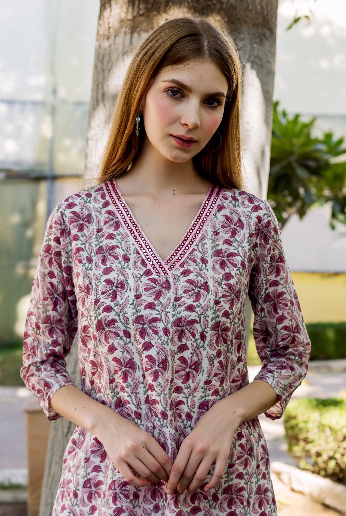 Model in a cream V-neck kurta with deep pink hand-block printed floral design.