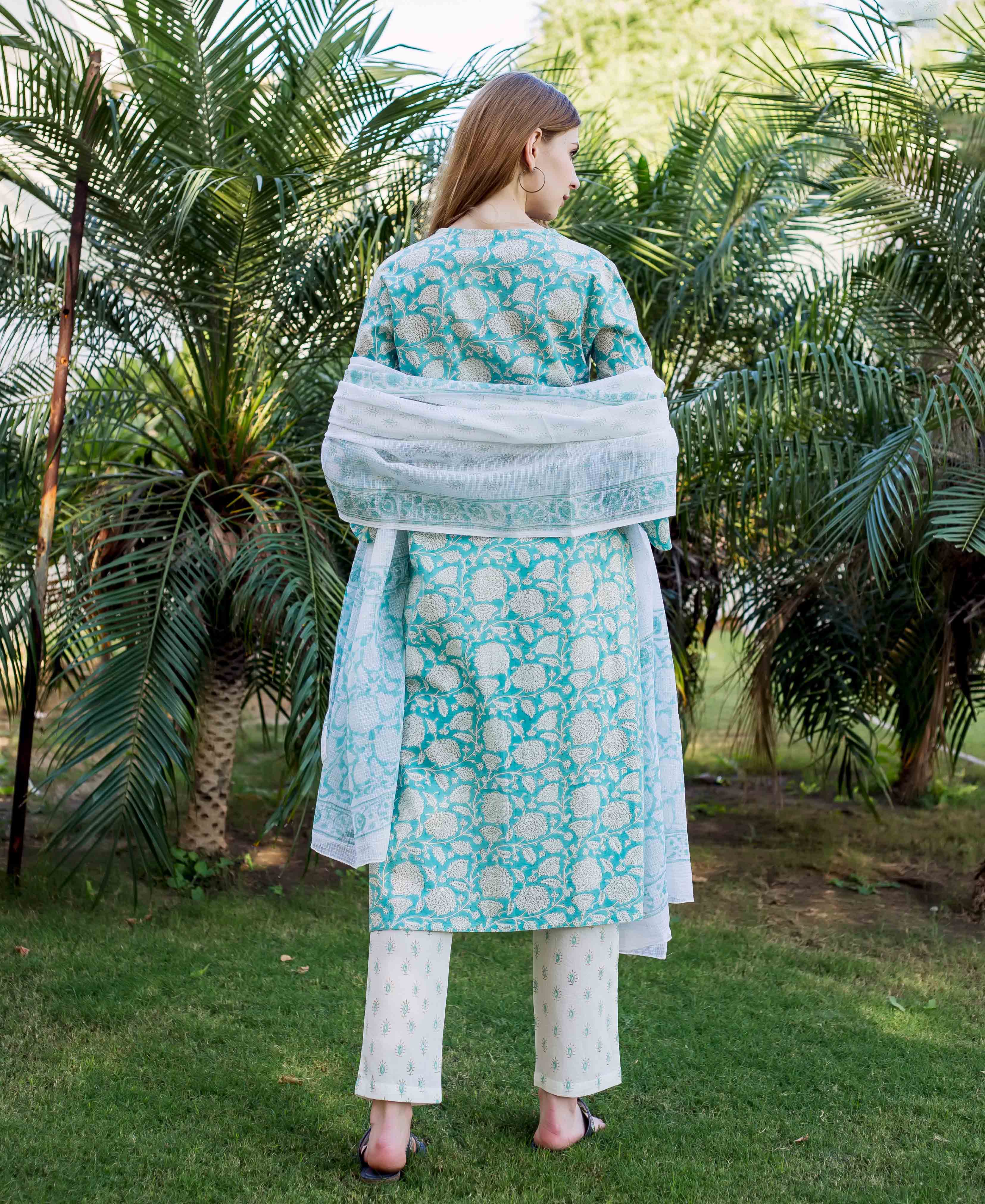 Back view of model wearing teal hand-block printed kurta, cream pants, and white dupatta.