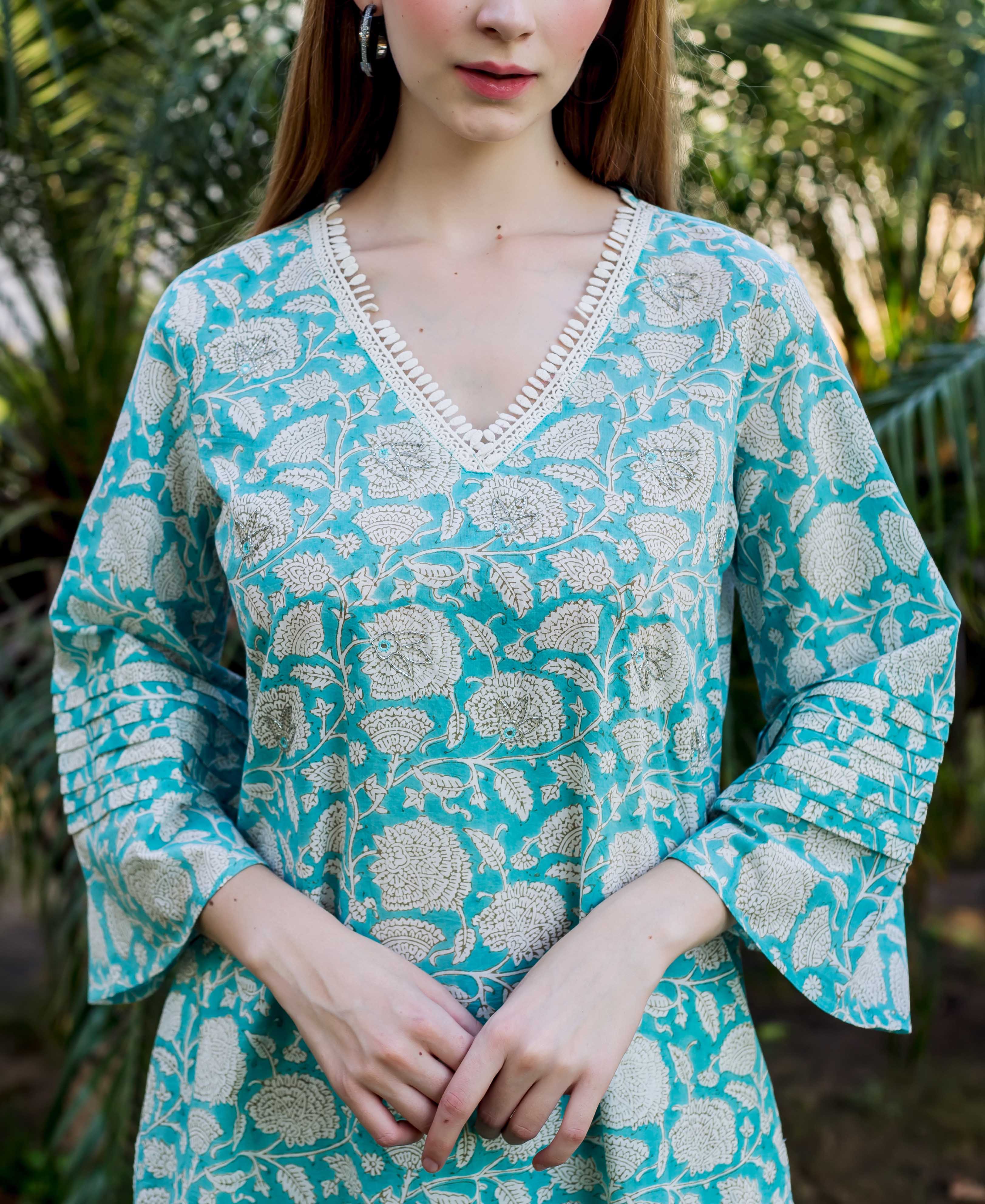 Model in a teal floral print kurta with embroidered V-neck and pleated bell sleeves.