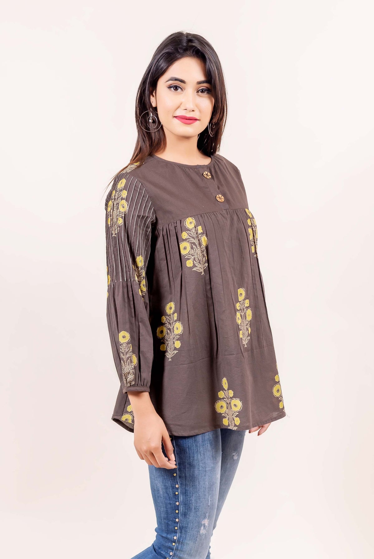 Front view of model in brown hand block printed cotton top with yellow florals and striped sleeves.