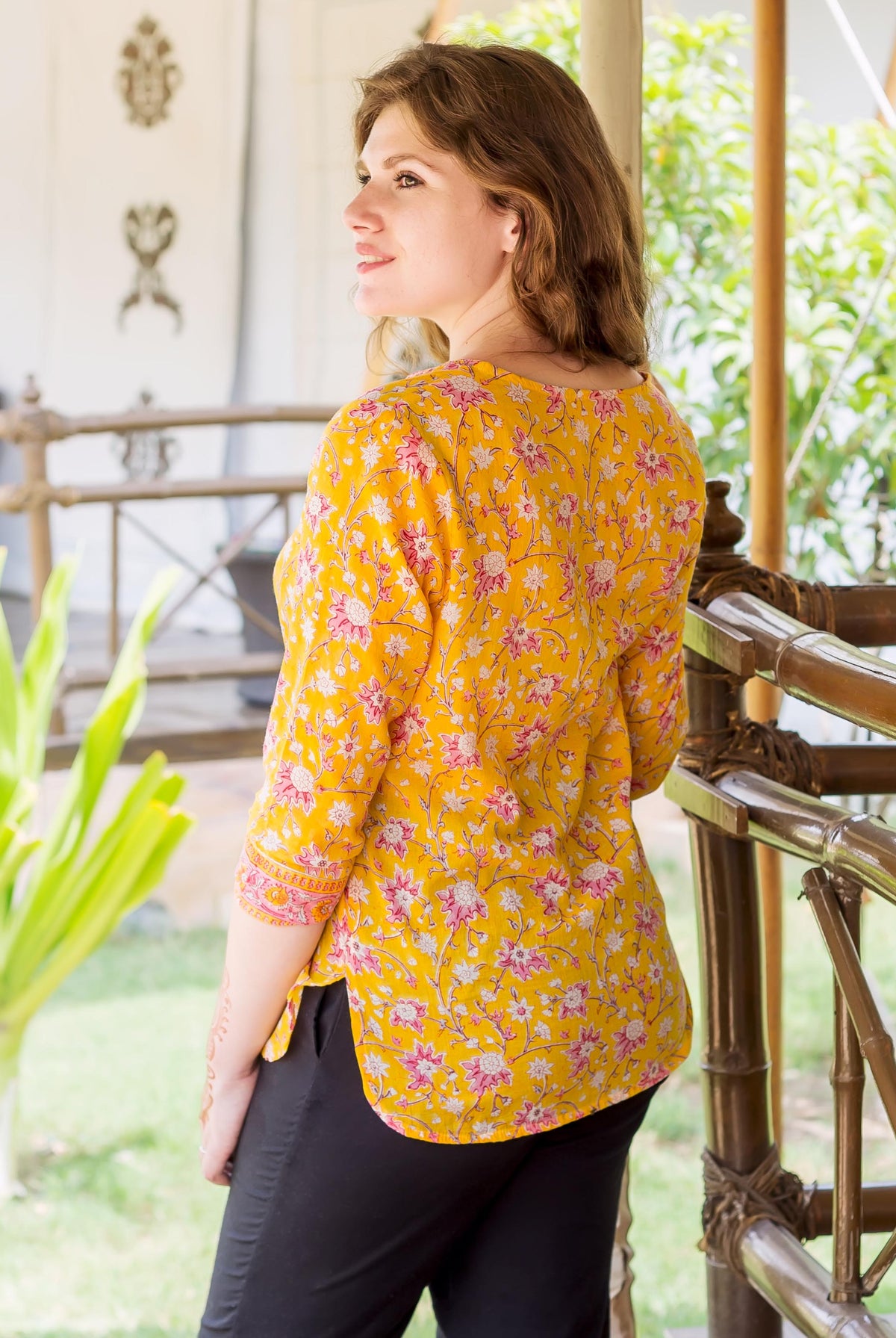 Model wearing a yellow and pink floral hand block printed ethnic top, back view.