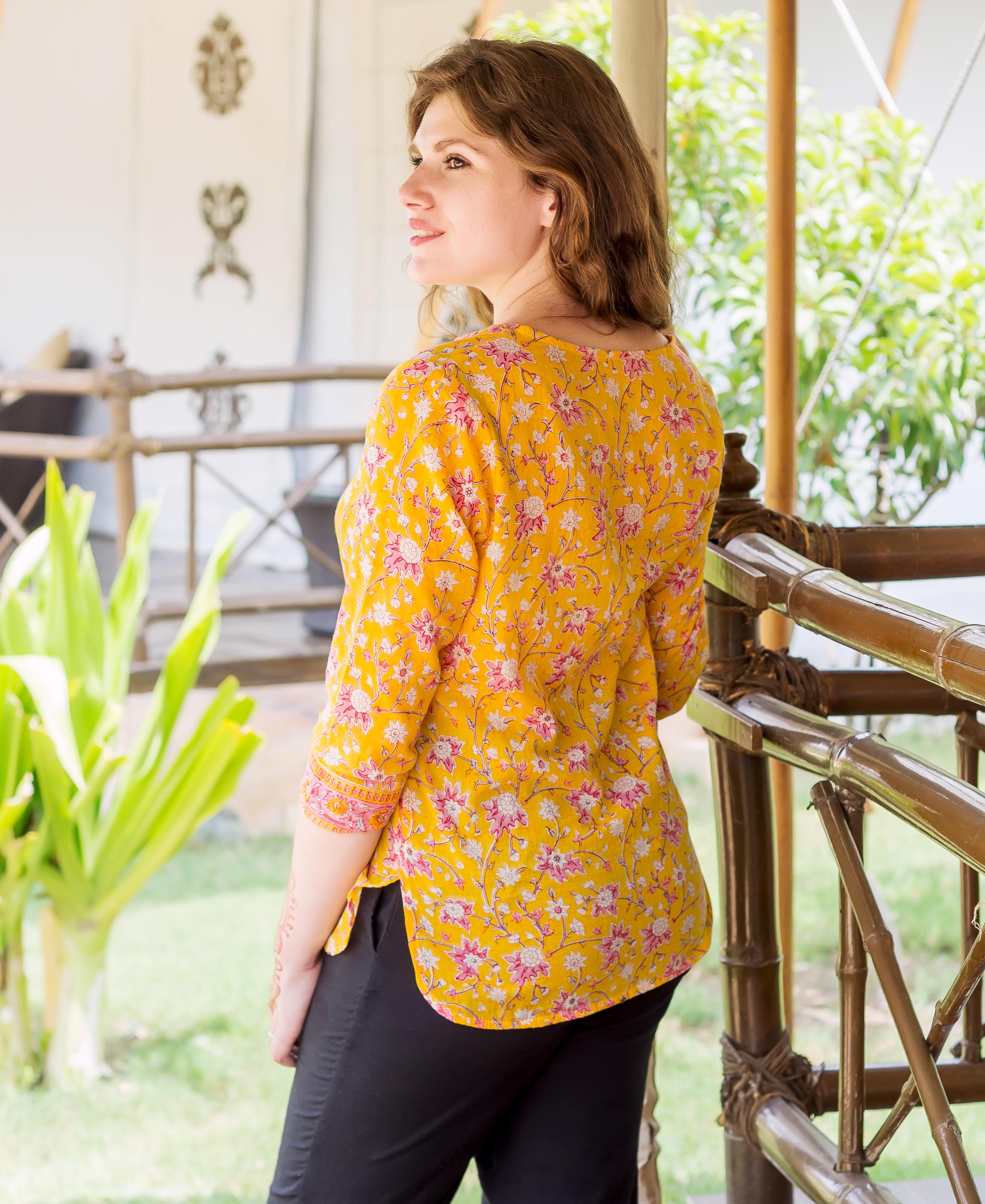 Model wearing a yellow and pink floral hand block printed ethnic top, back view.