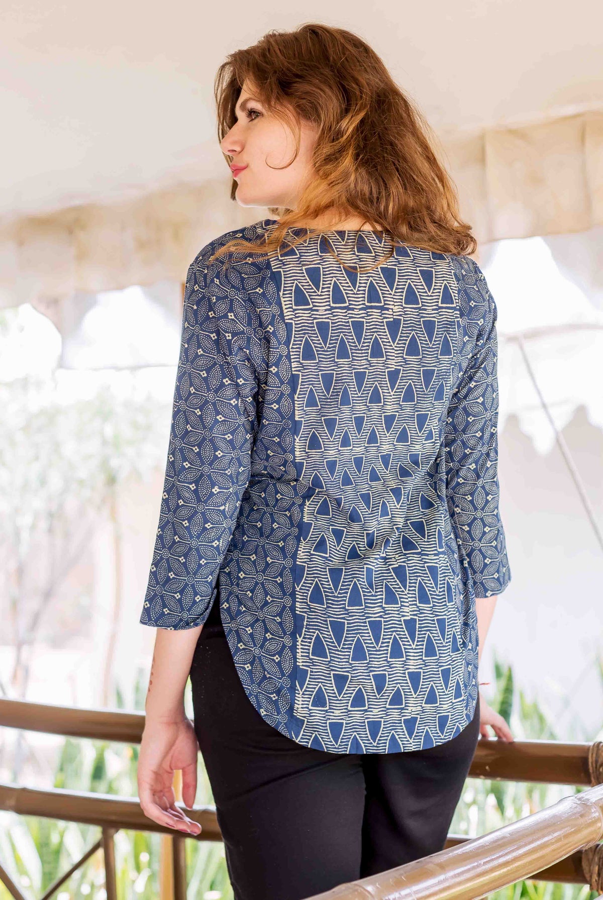 Back view of model in indigo hand-block-printed ethnic top with geometric and floral designs.