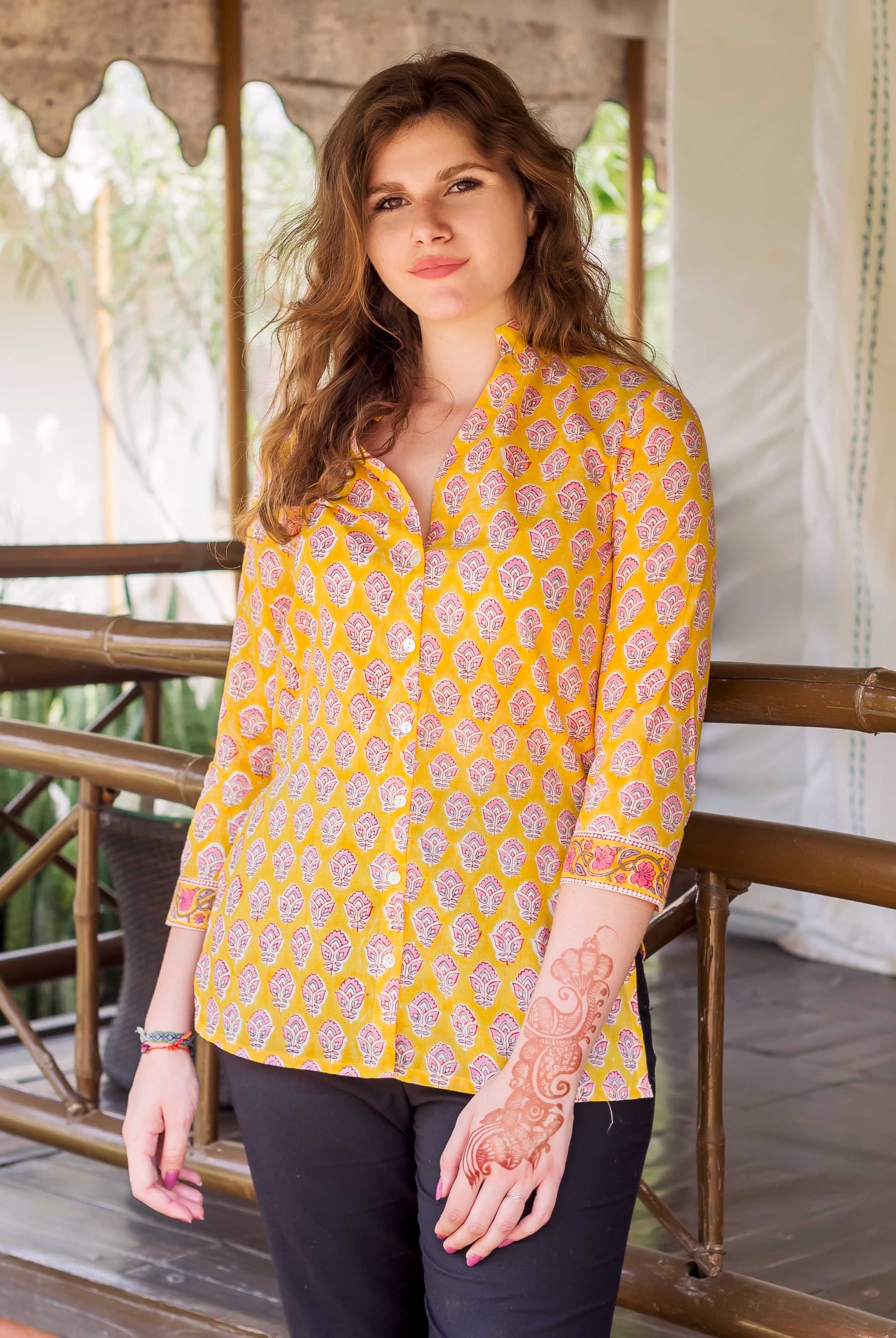 Woman wearing a yellow block-printed button-down shirt with pink paisley motifs, front view.