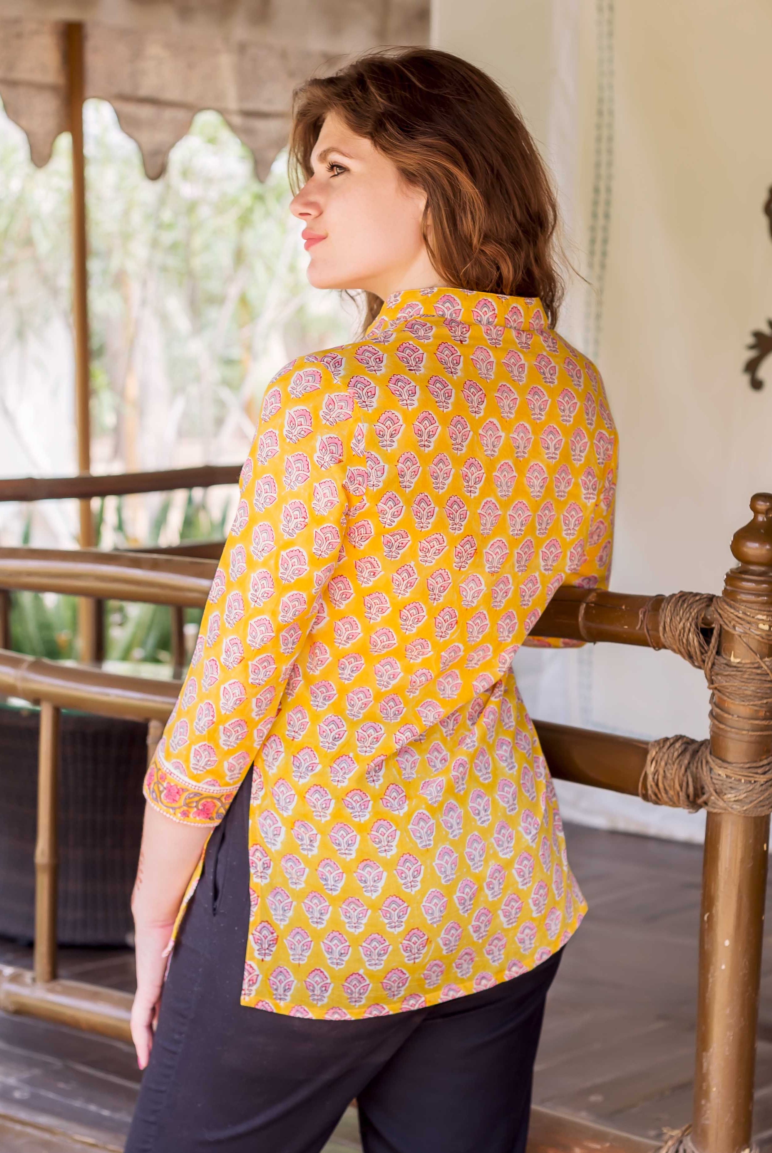 Model wearing yellow hand-block-printed shirt with pink ethnic floral patterns, back view.