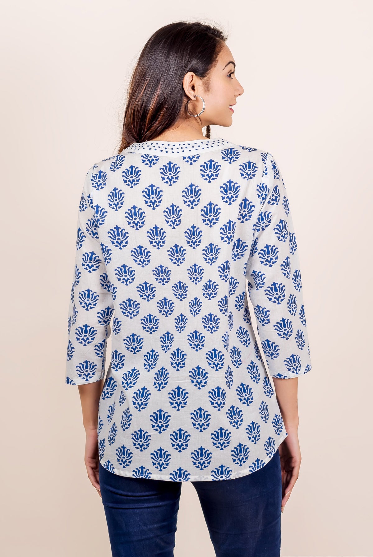 White and blue hand block printed V-neck top on a model, back view.