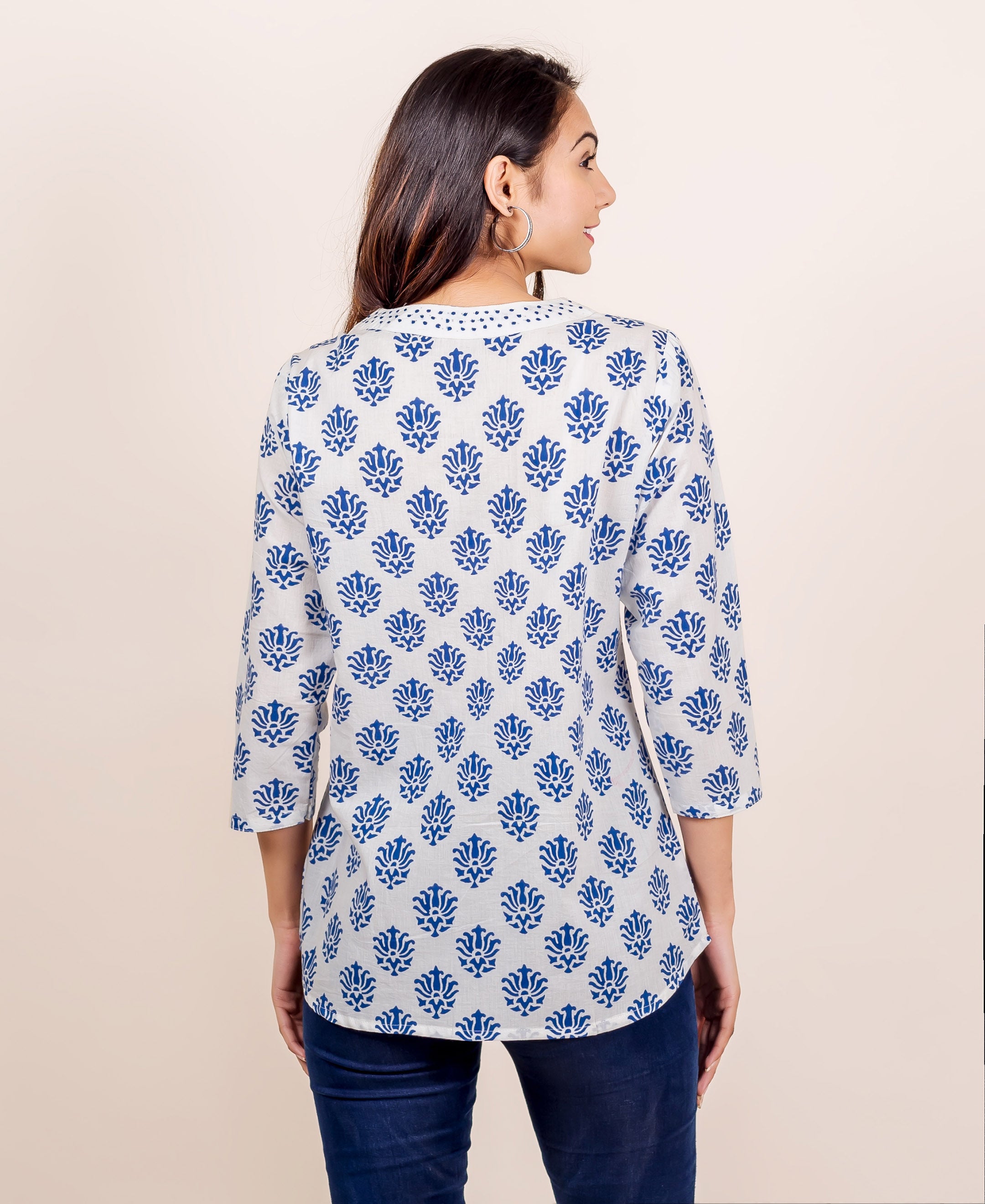 White and blue hand block printed V-neck top on a model, back view.