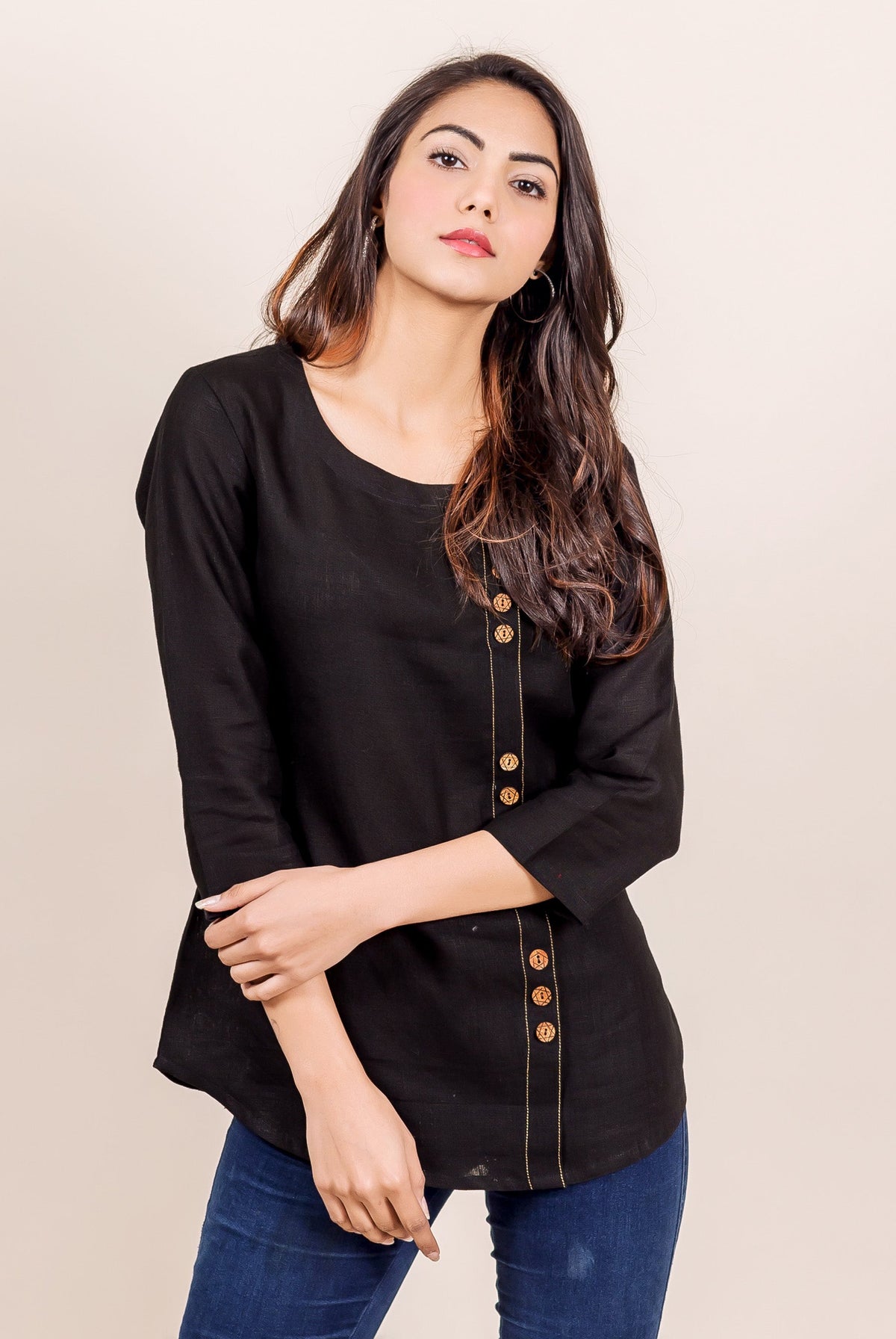 Front view model in a black linen top with off-center vertical golden decorative button stitch line.
