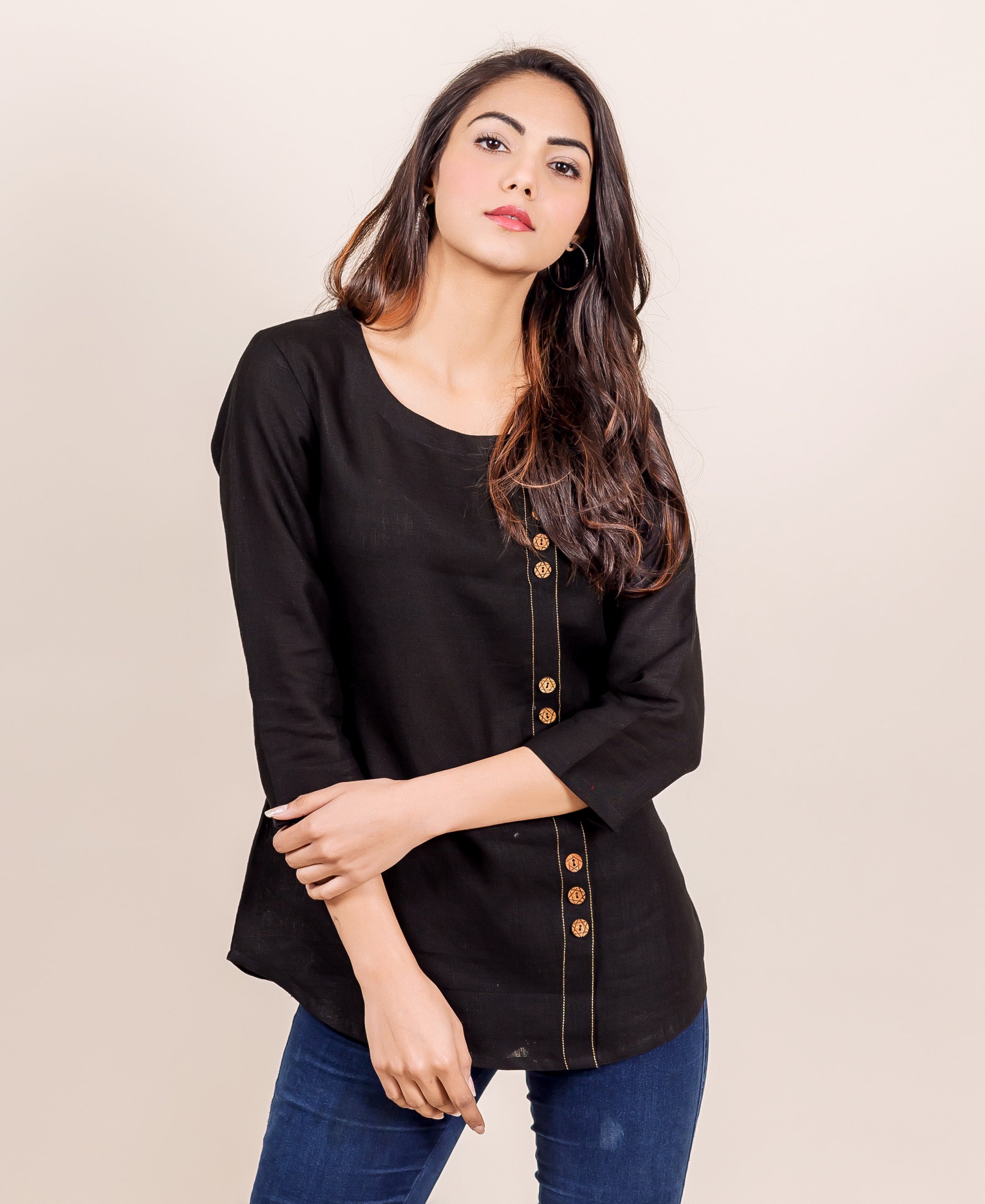 Front view model in a black linen top with off-center vertical golden decorative button stitch line.