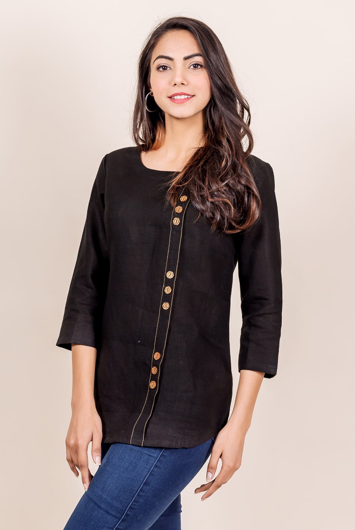 Front view of model wearing black linen top with golden buttons and contrasting stitch.