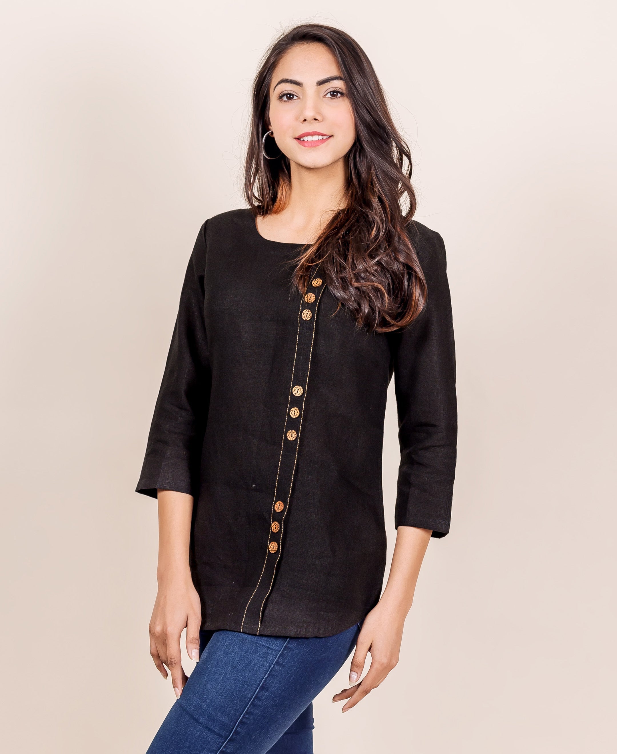 Front view of model wearing black linen top with golden buttons and contrasting stitch.