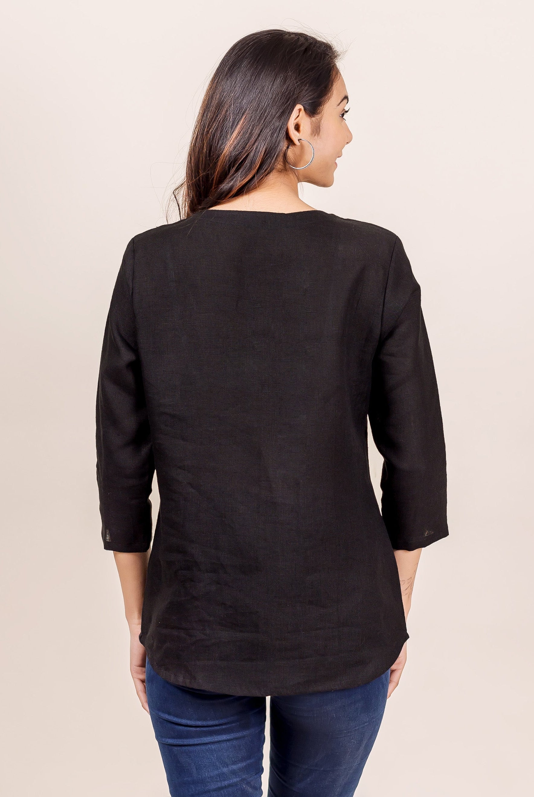 Back view of woman in plain black linen top with three-quarter sleeves.