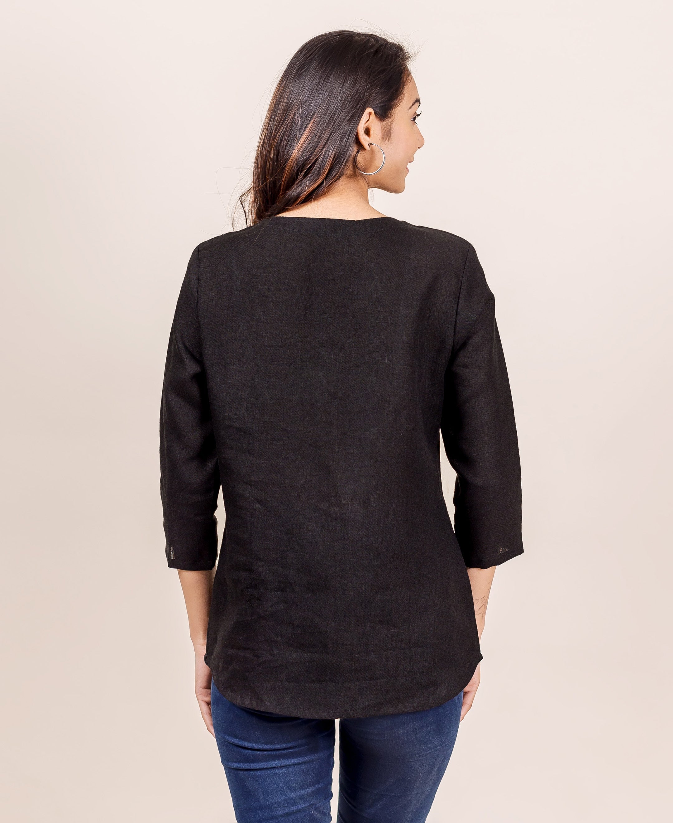 Back view of woman in plain black linen top with three-quarter sleeves.