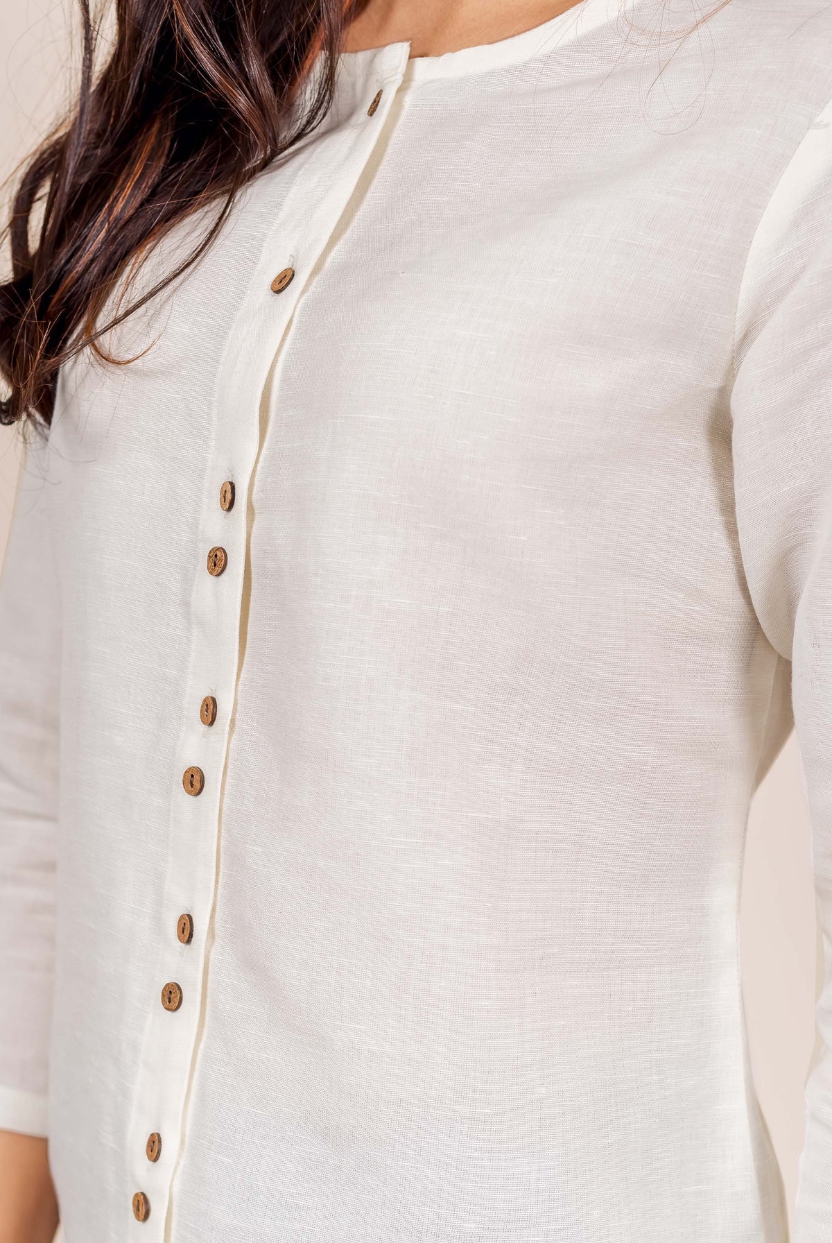 Close-up of model wearing antique white linen top with brown wooden buttons on front placket.