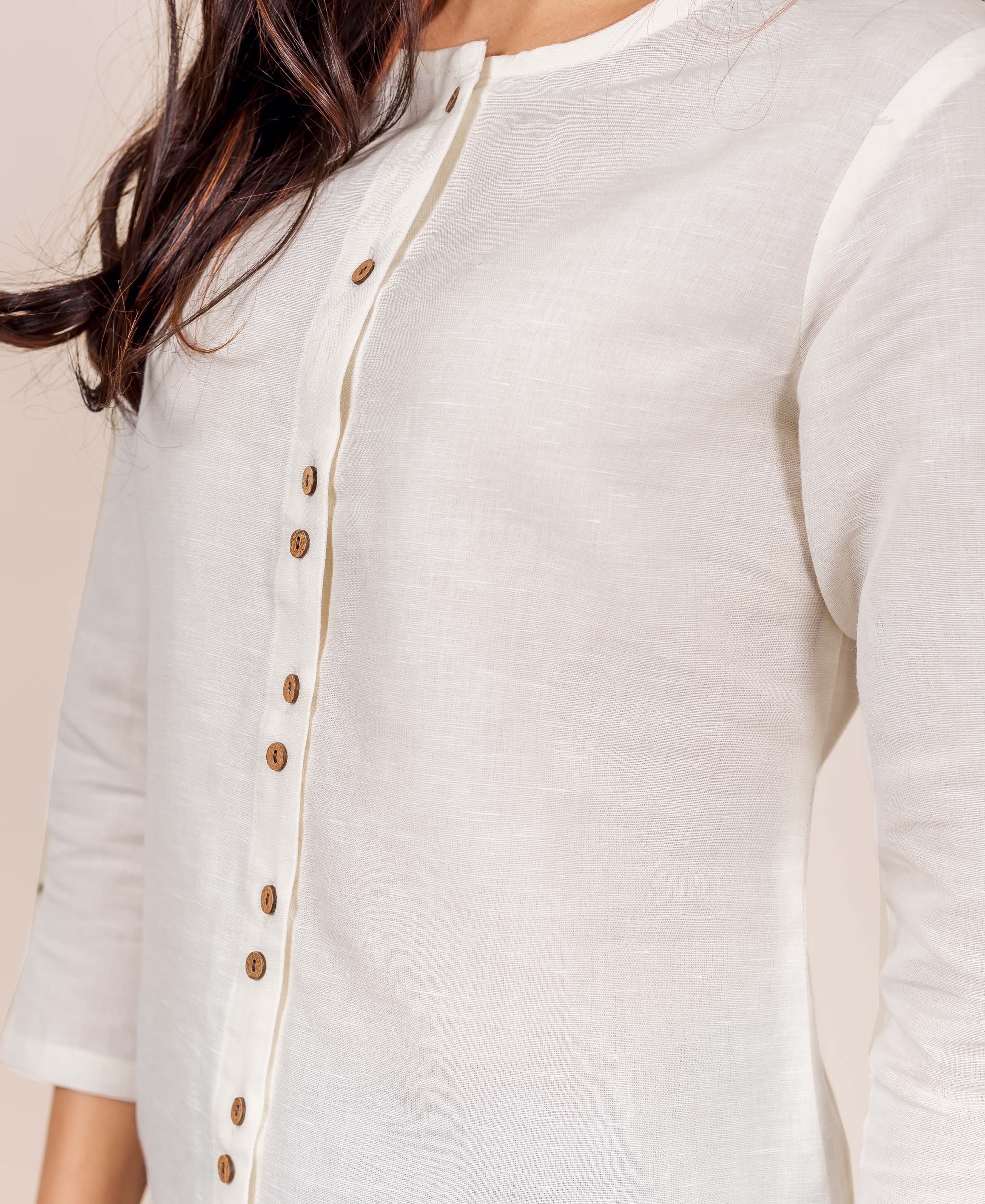 Close-up of model wearing antique white linen top with brown wooden buttons on front placket.