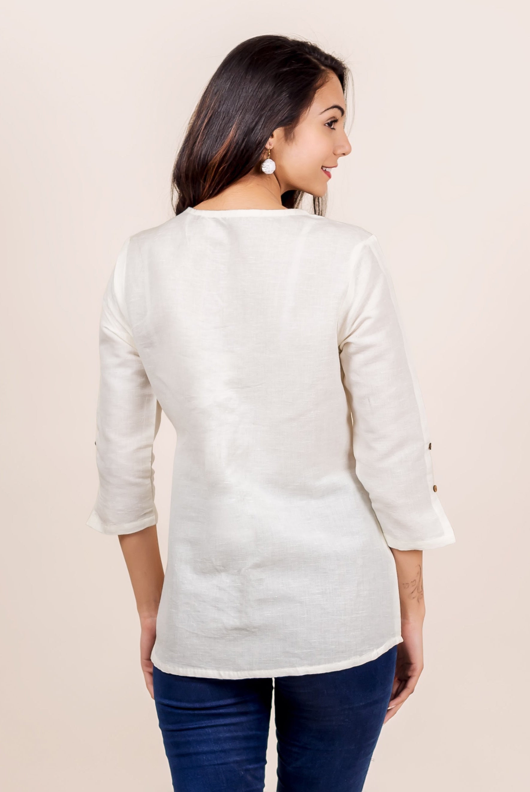 Model in antique white linen top, back view, with three-quarter sleeves and button details.