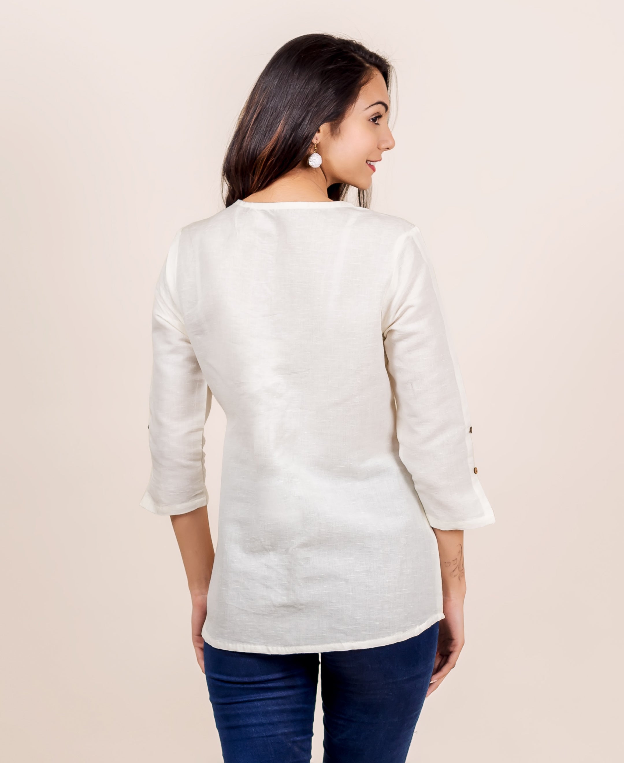 Model in antique white linen top, back view, with three-quarter sleeves and button details.