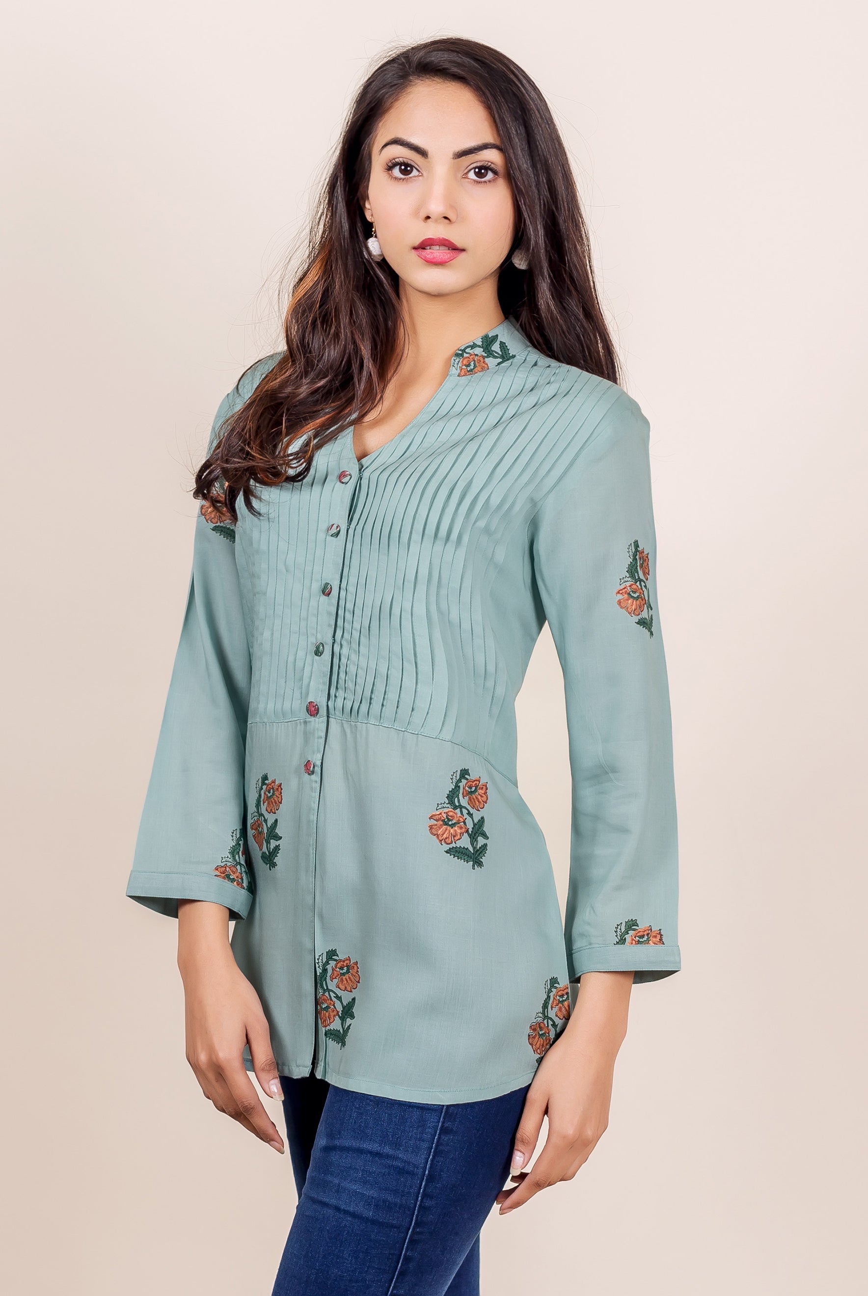Model in a turquoise blue hand-block printed pin tuck top with orange floral patterns.