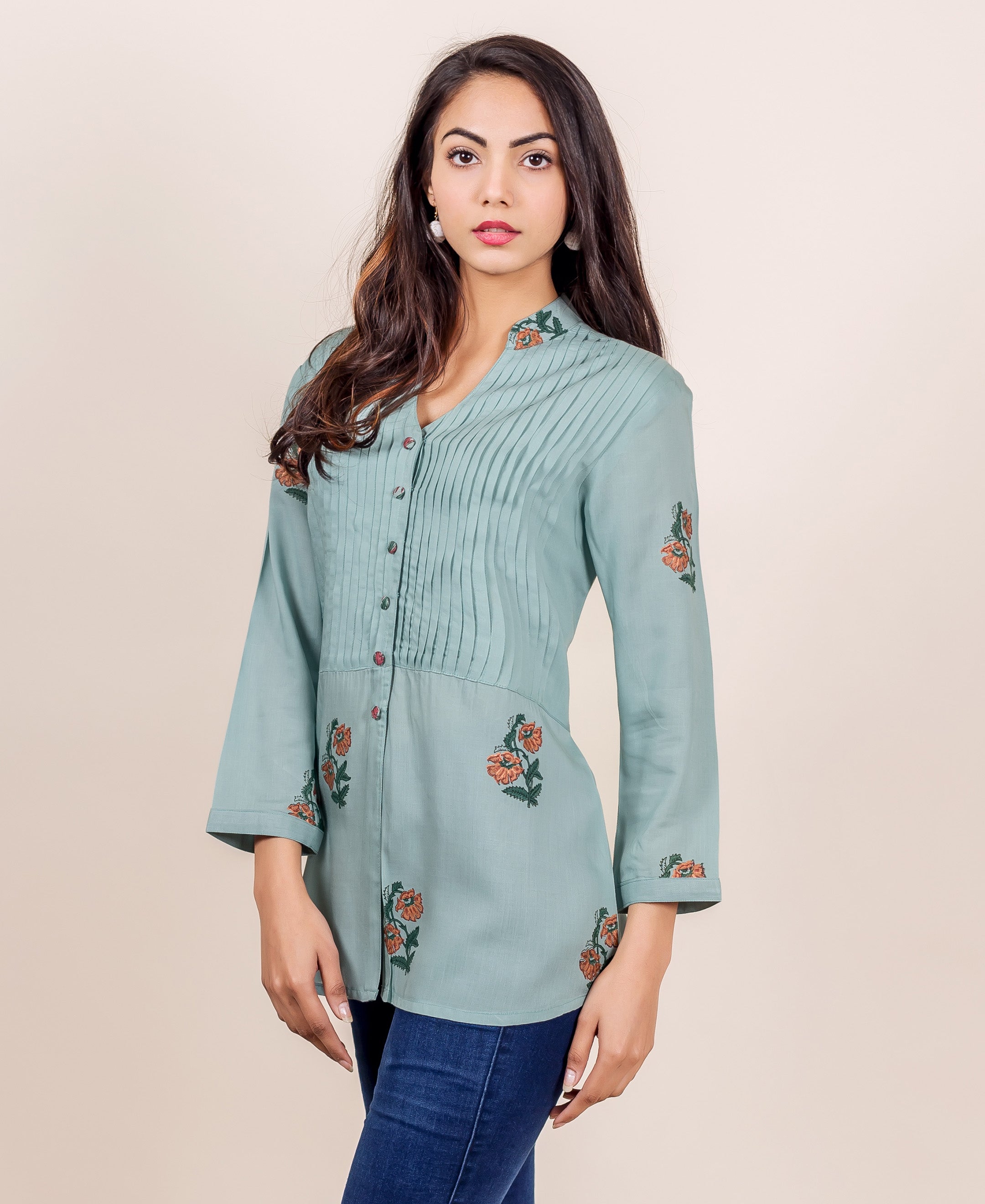 Model in a turquoise blue hand-block printed pin tuck top with orange floral patterns.
