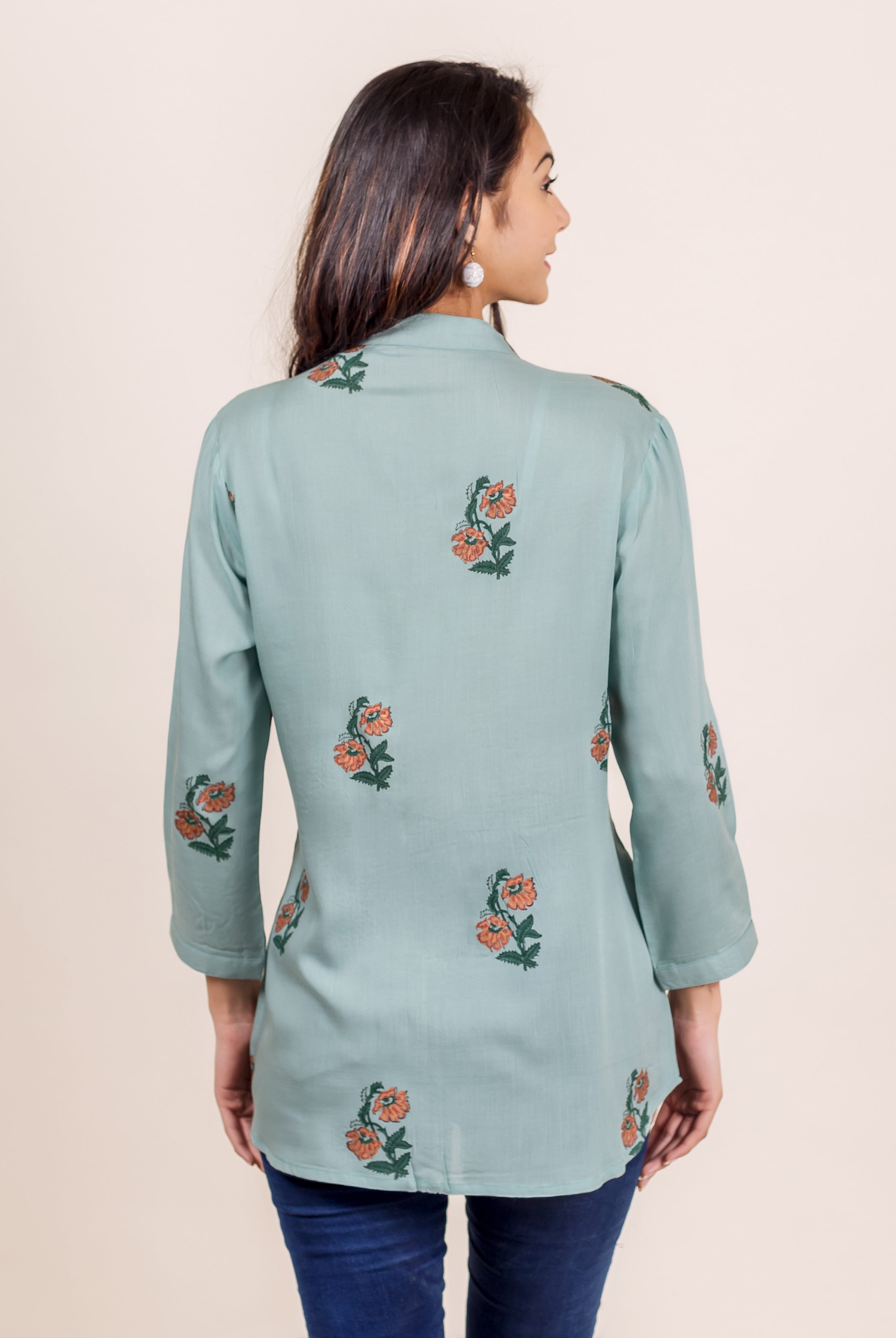 Turquoise blue hand block printed pin tuck top with floral pattern on a model.