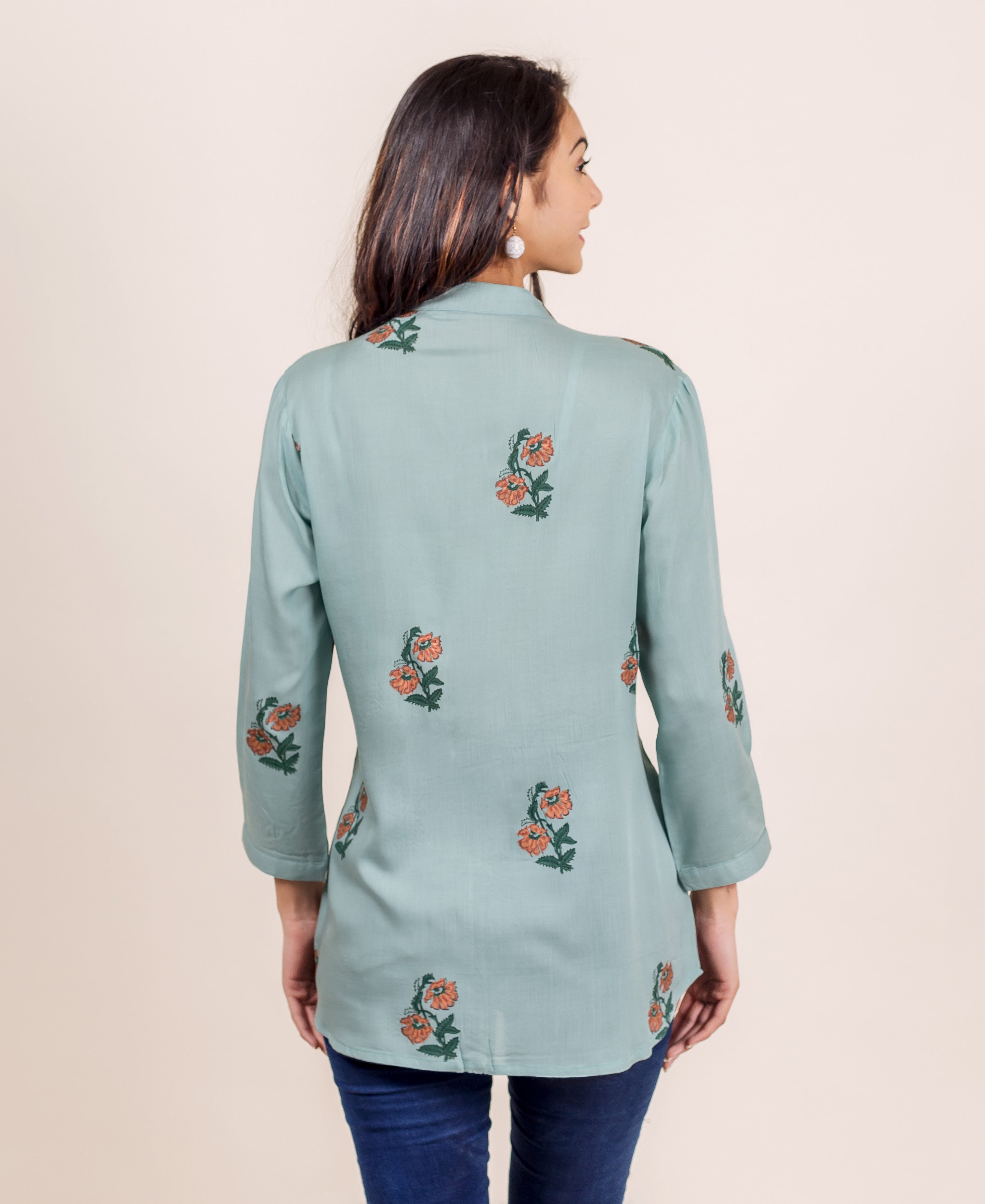 Turquoise blue hand block printed pin tuck top with floral pattern on a model.