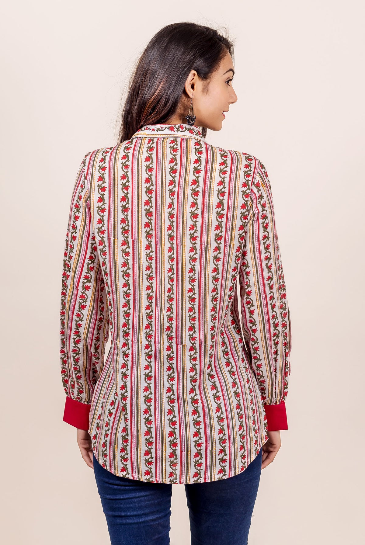 Woman from back wearing white, red, green hand block-printed floral striped shirt.