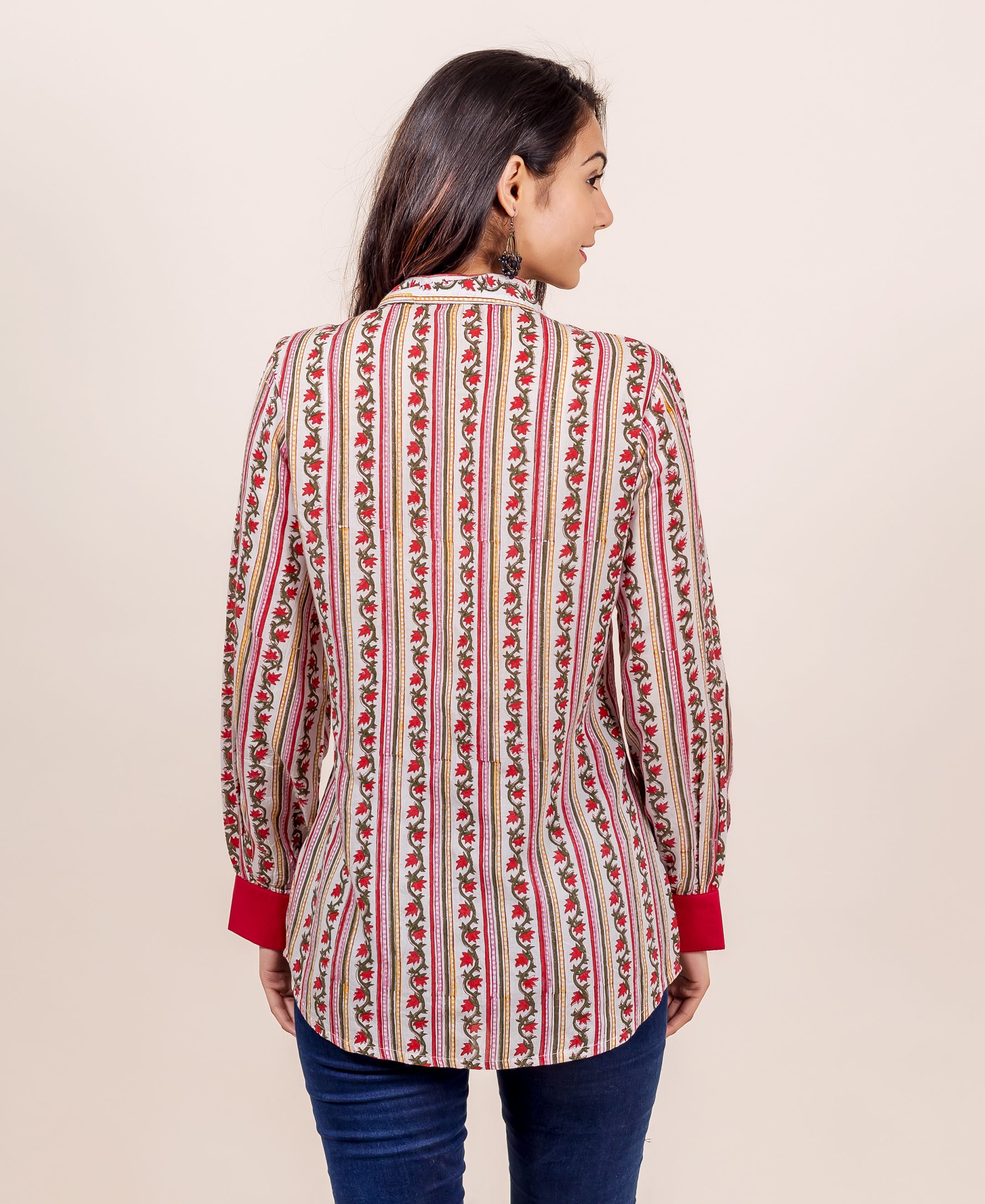 Woman from back wearing white, red, green hand block-printed floral striped shirt.