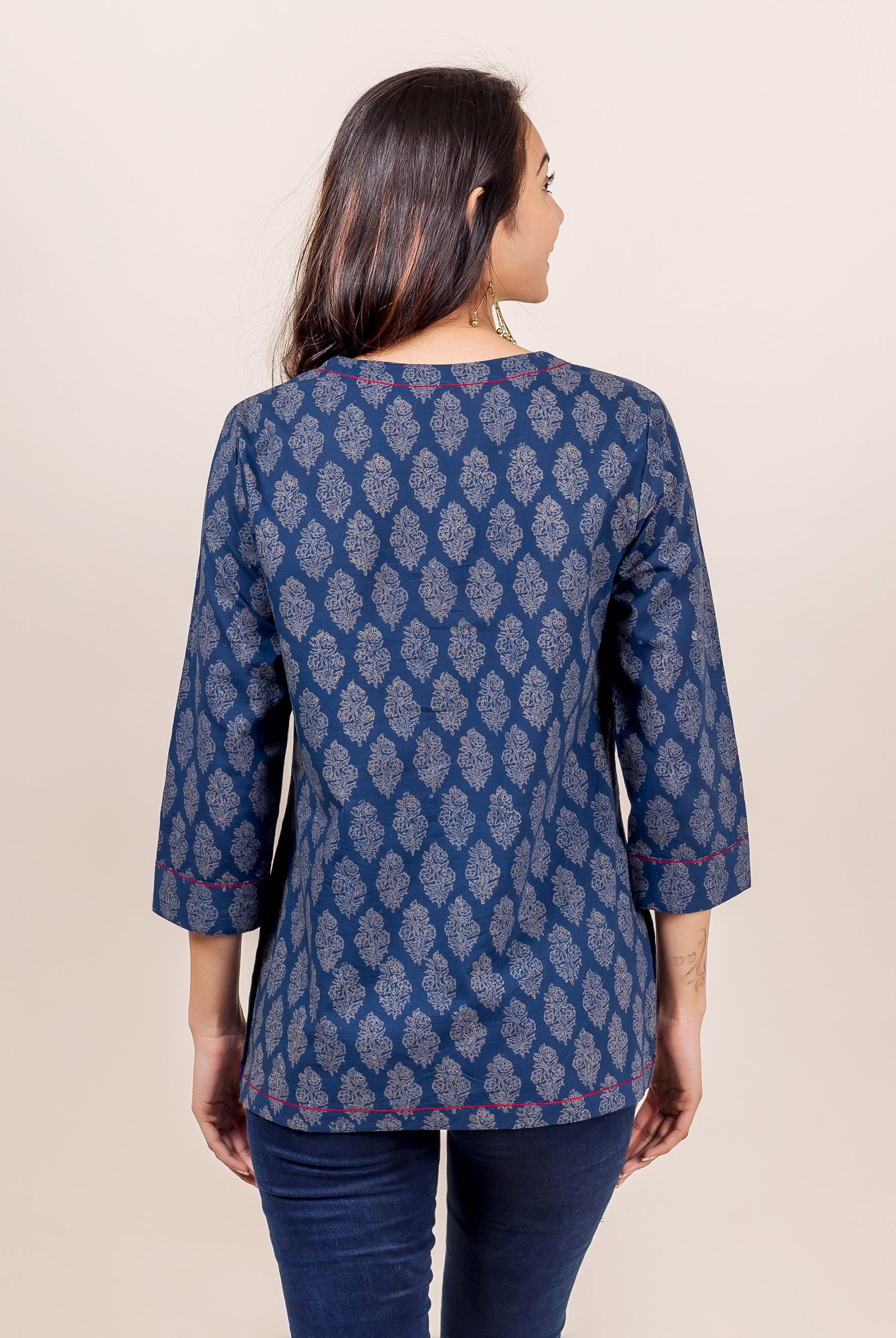 Back view of model wearing indigo hand block printed top with red piping details.