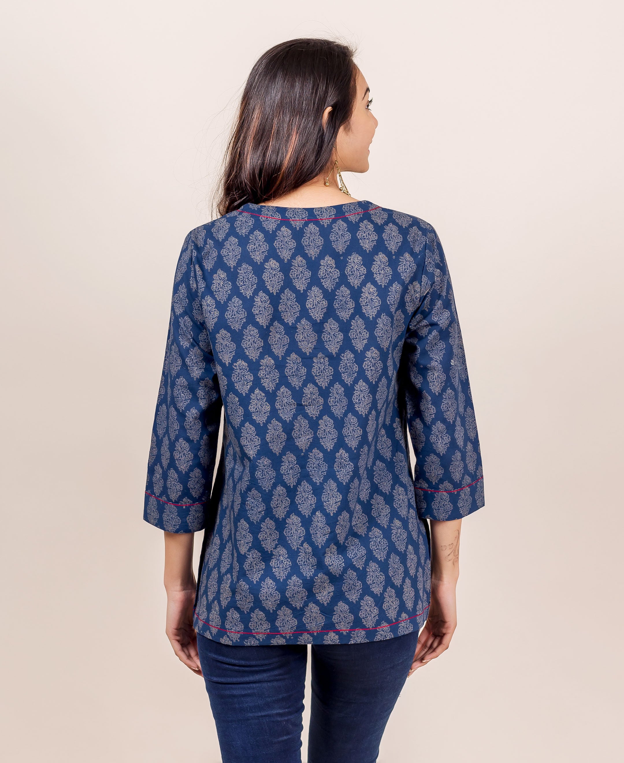 Back view of model wearing indigo hand block printed top with red piping details.