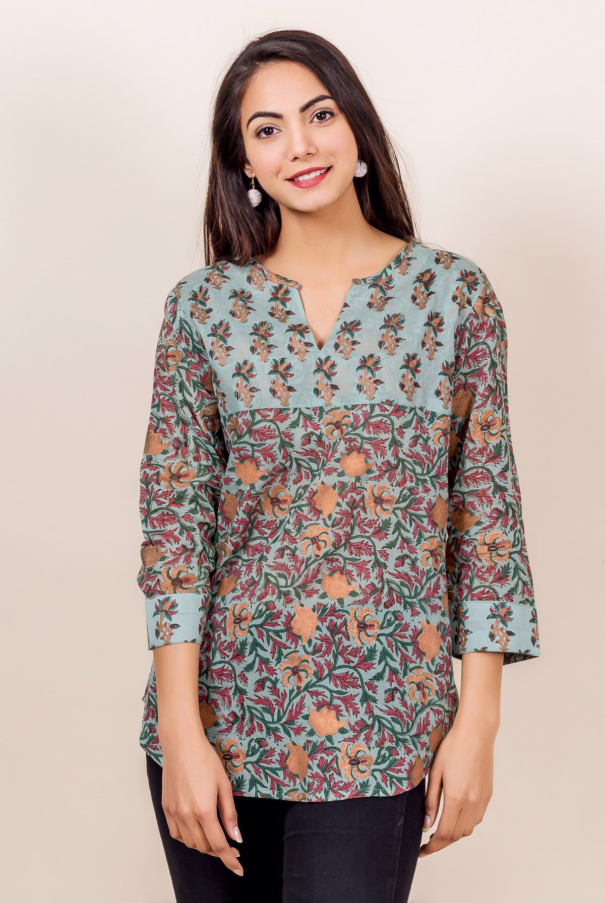 Front-facing model wears a light blue block-printed cotton top with green and orange floral designs.