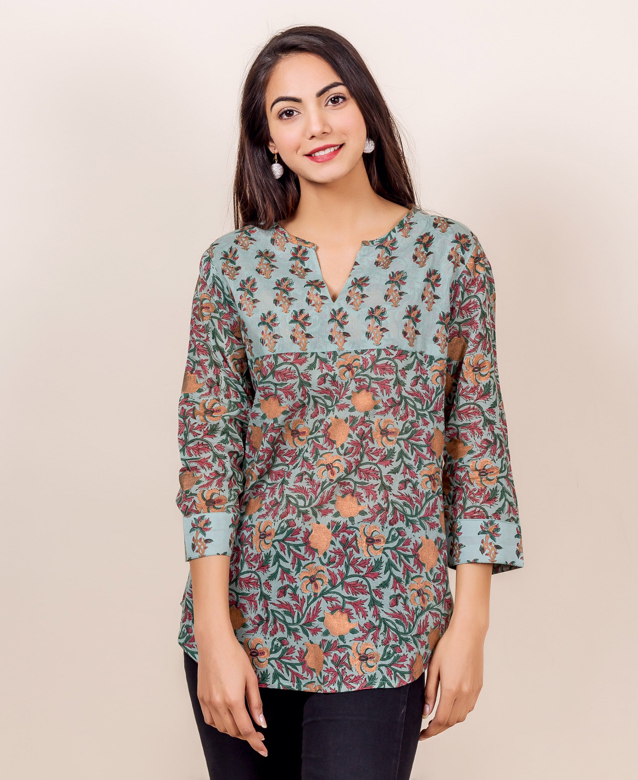 Front-facing model wears a light blue block-printed cotton top with green and orange floral designs.