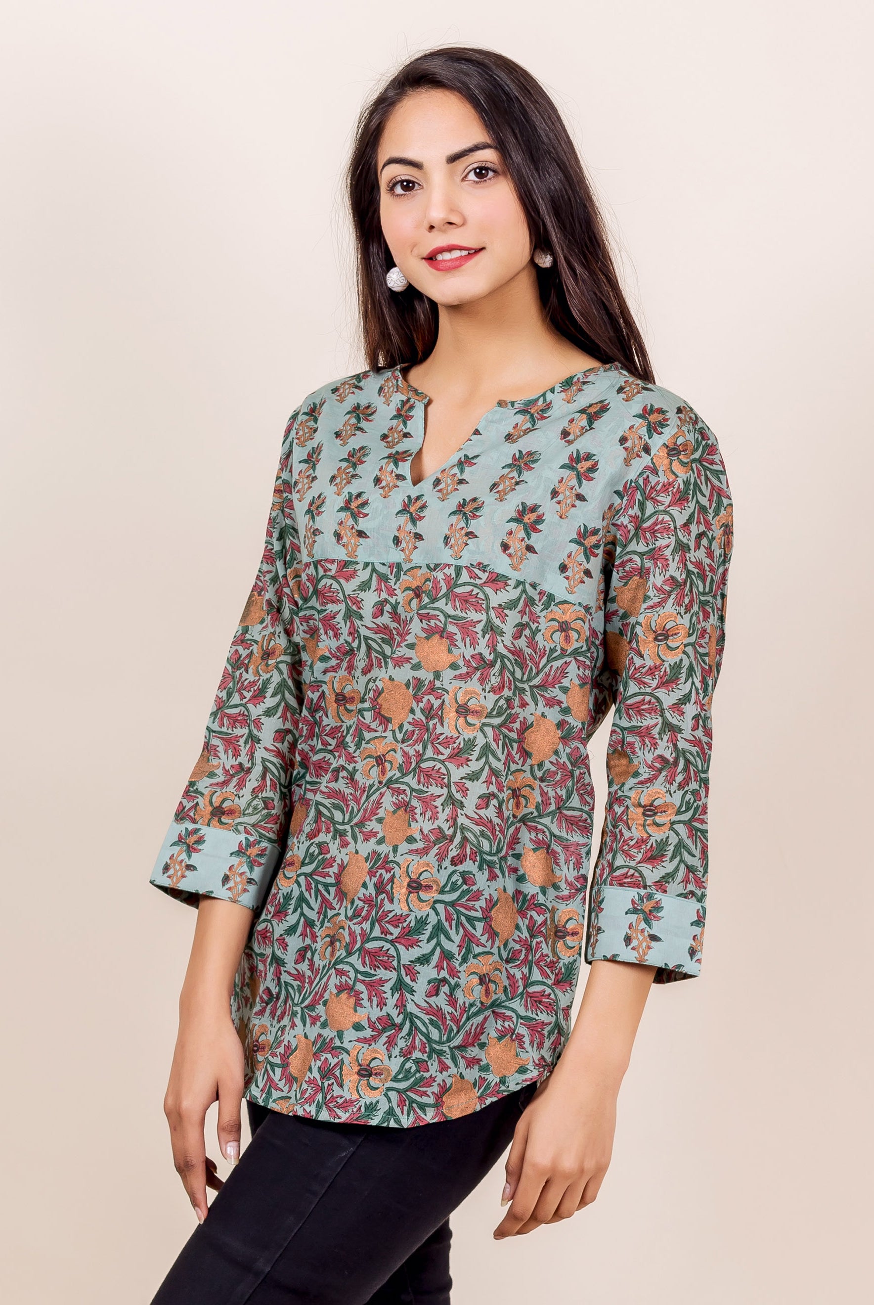 Woman wearing blue, orange, red, and green floral hand-block-printed cotton top with 3/4 sleeves.