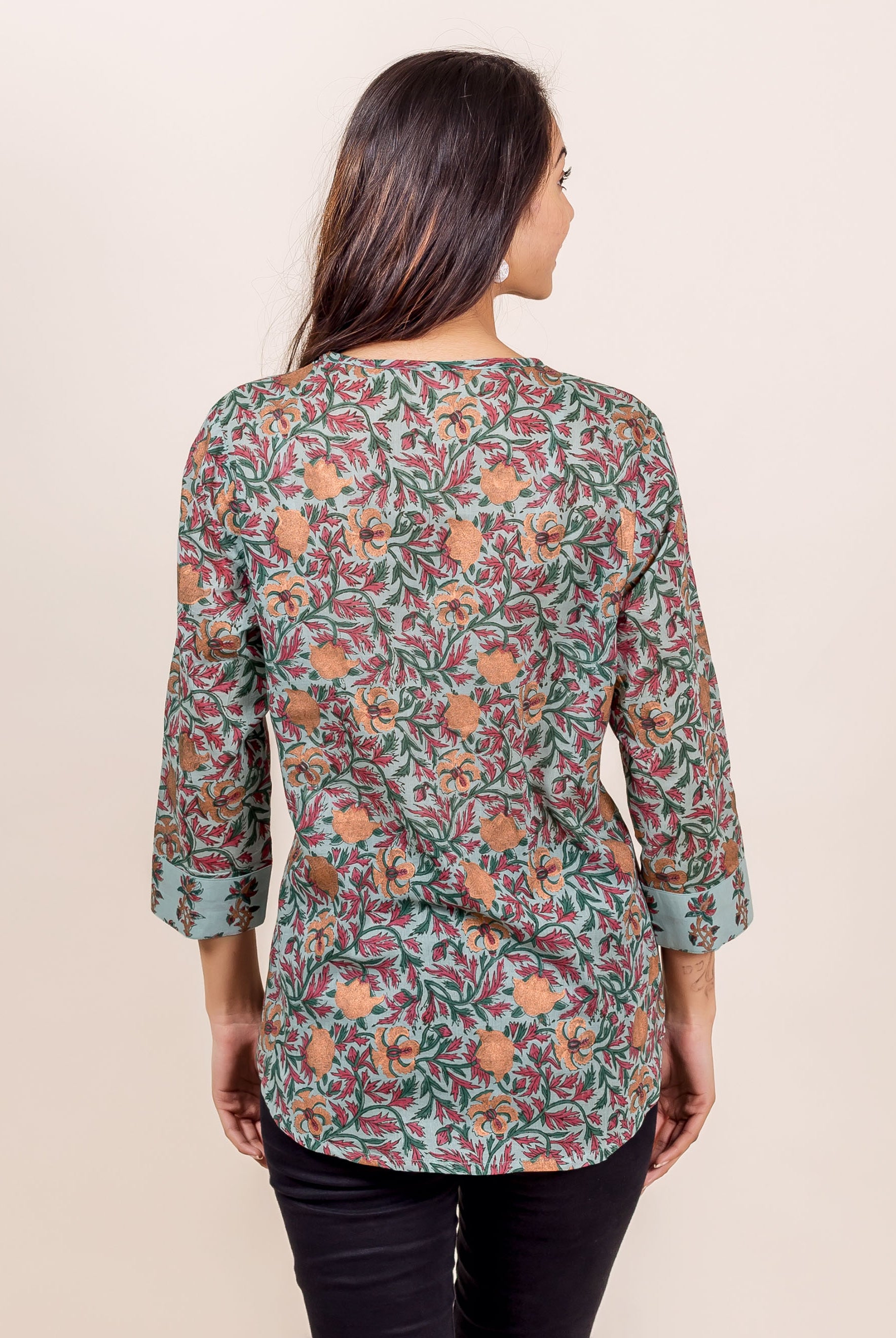 A model wearing a blue floral hand-block-printed cotton top with black pants.