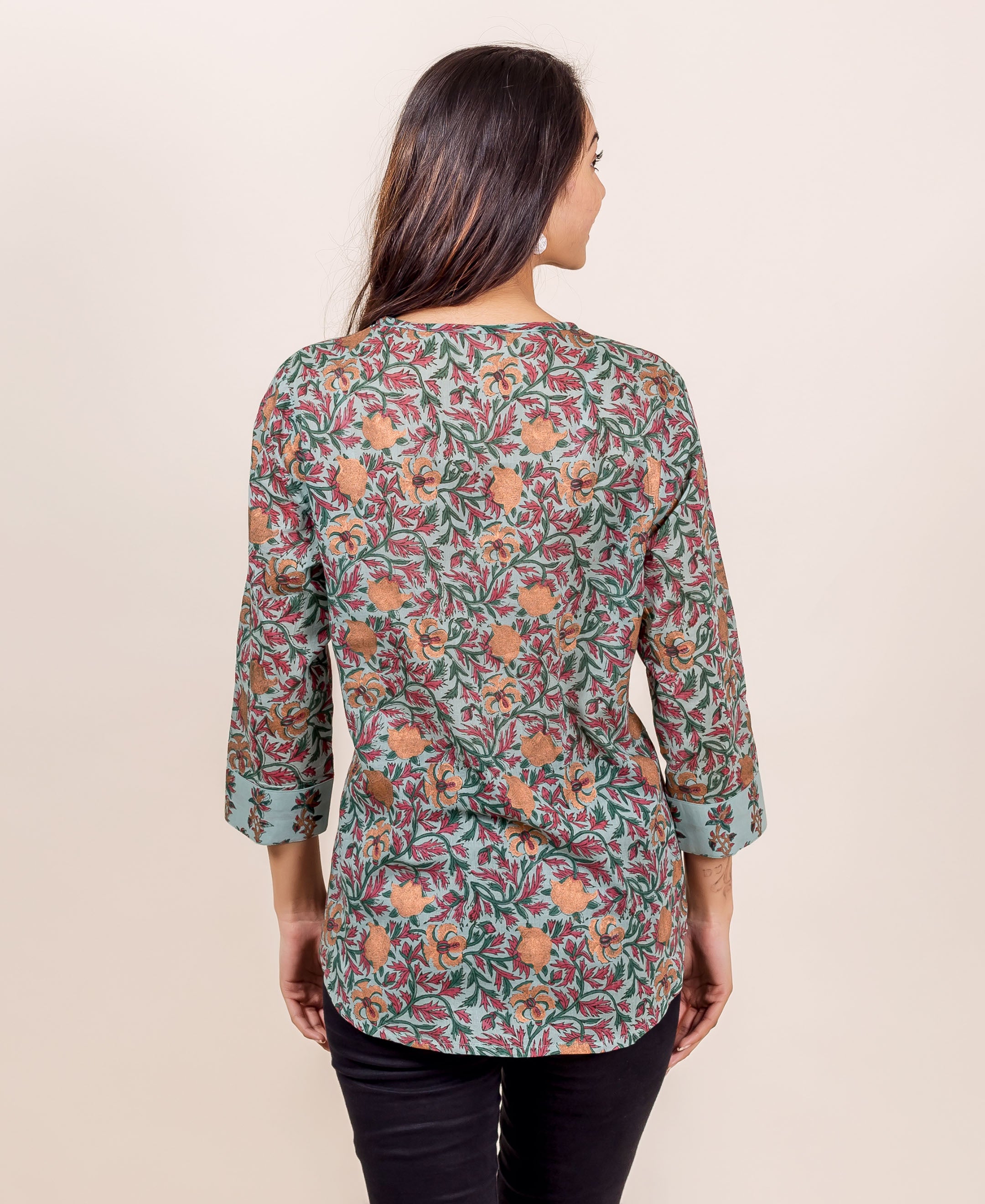 A model wearing a blue floral hand-block-printed cotton top with black pants.