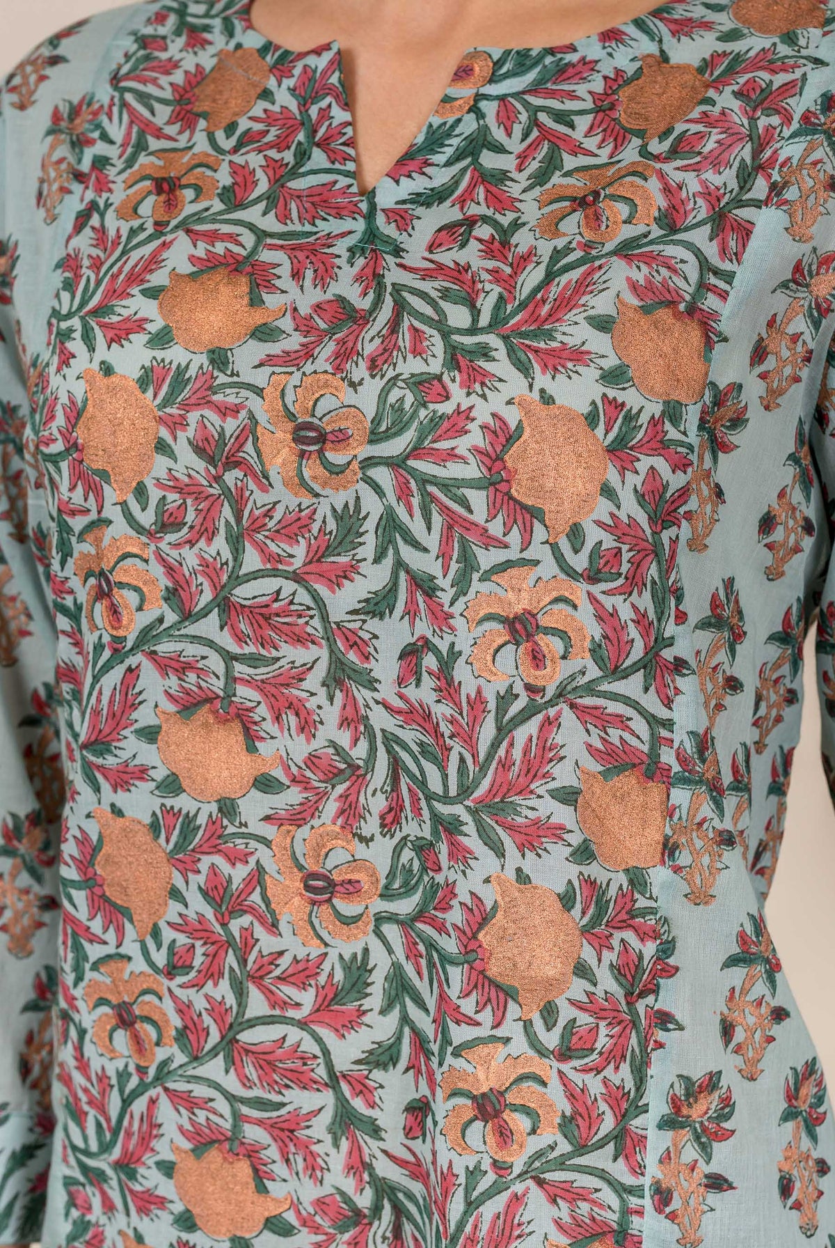 A model wears a light blue top with a floral pattern in shades of pink and green.