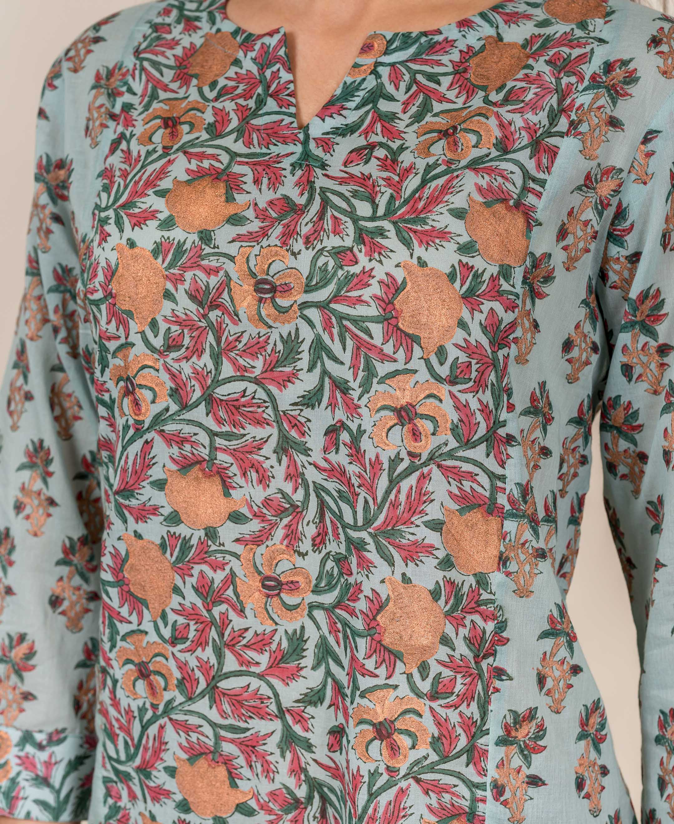 A model wears a light blue top with a floral pattern in shades of pink and green.