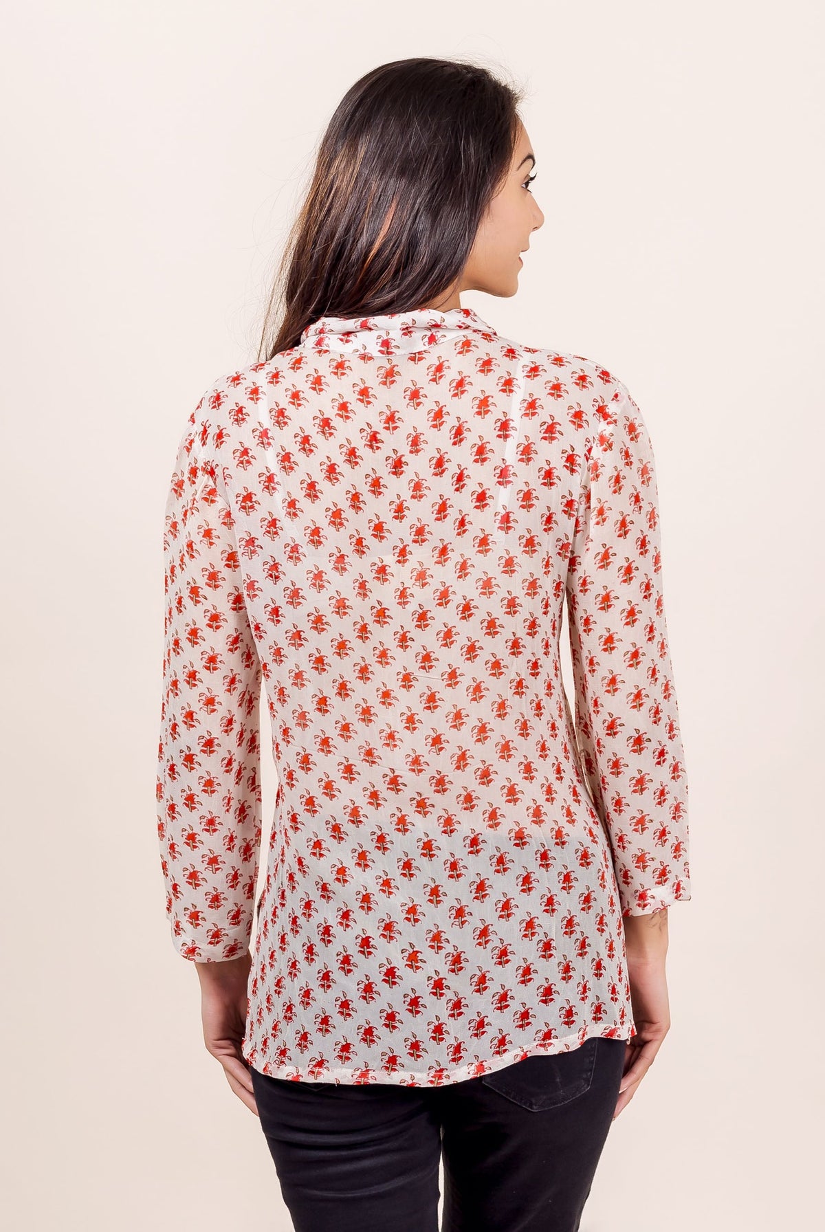 Back view of a model in a white georgette block-printed shirt with red ethnic patterns.