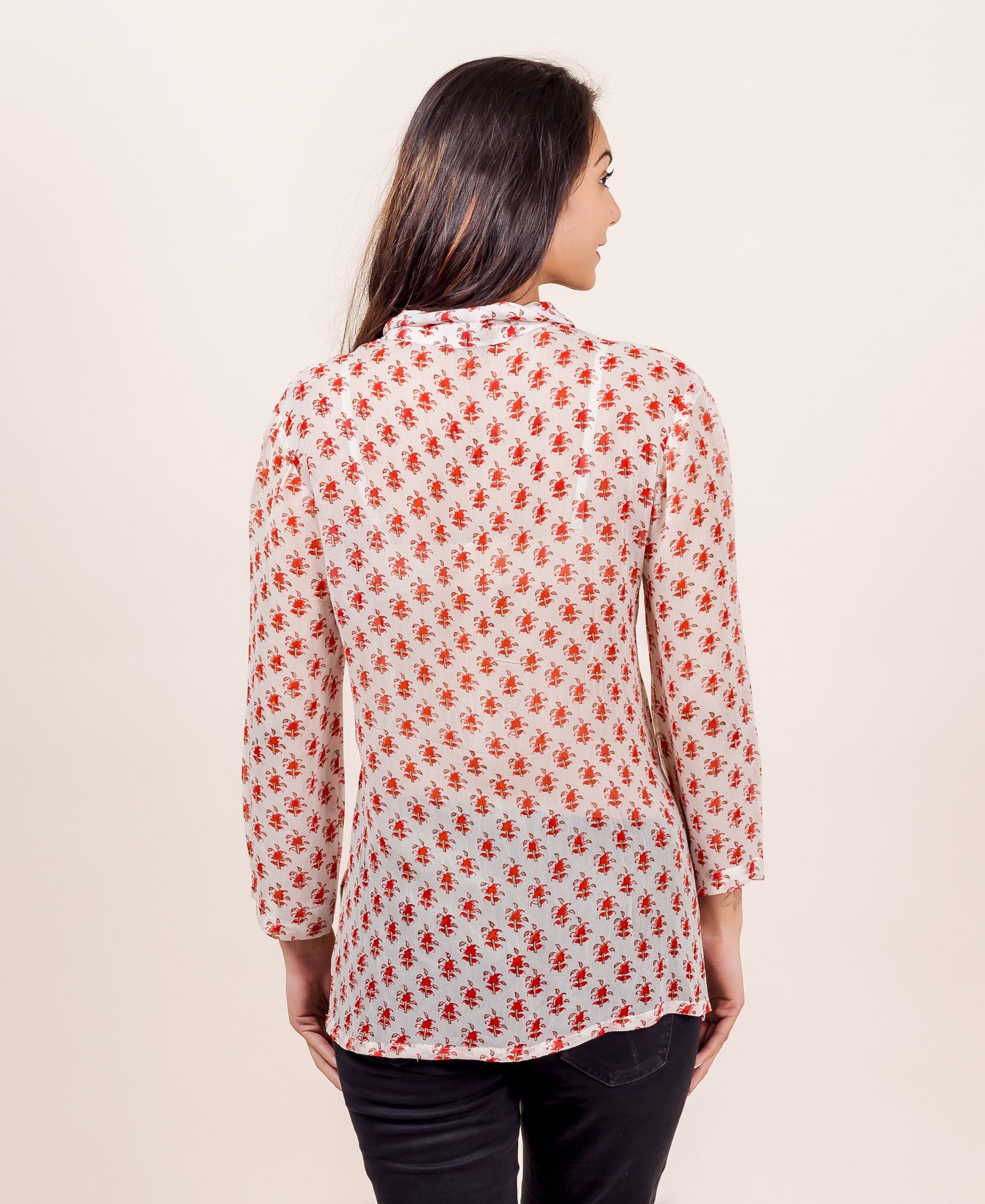 Back view of a model in a white georgette block-printed shirt with red ethnic patterns.