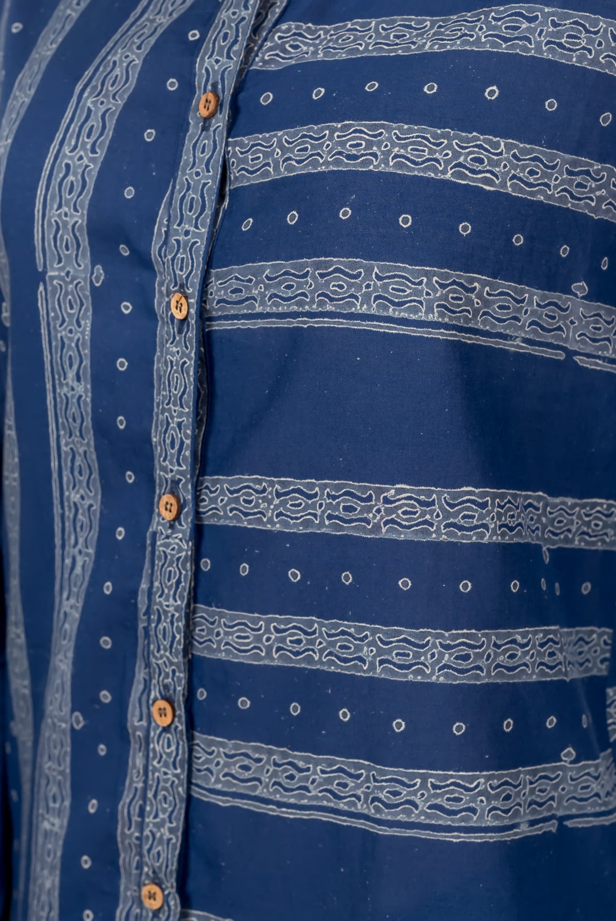 A close-up of a blue, block-printed button-down shirt with white designs.