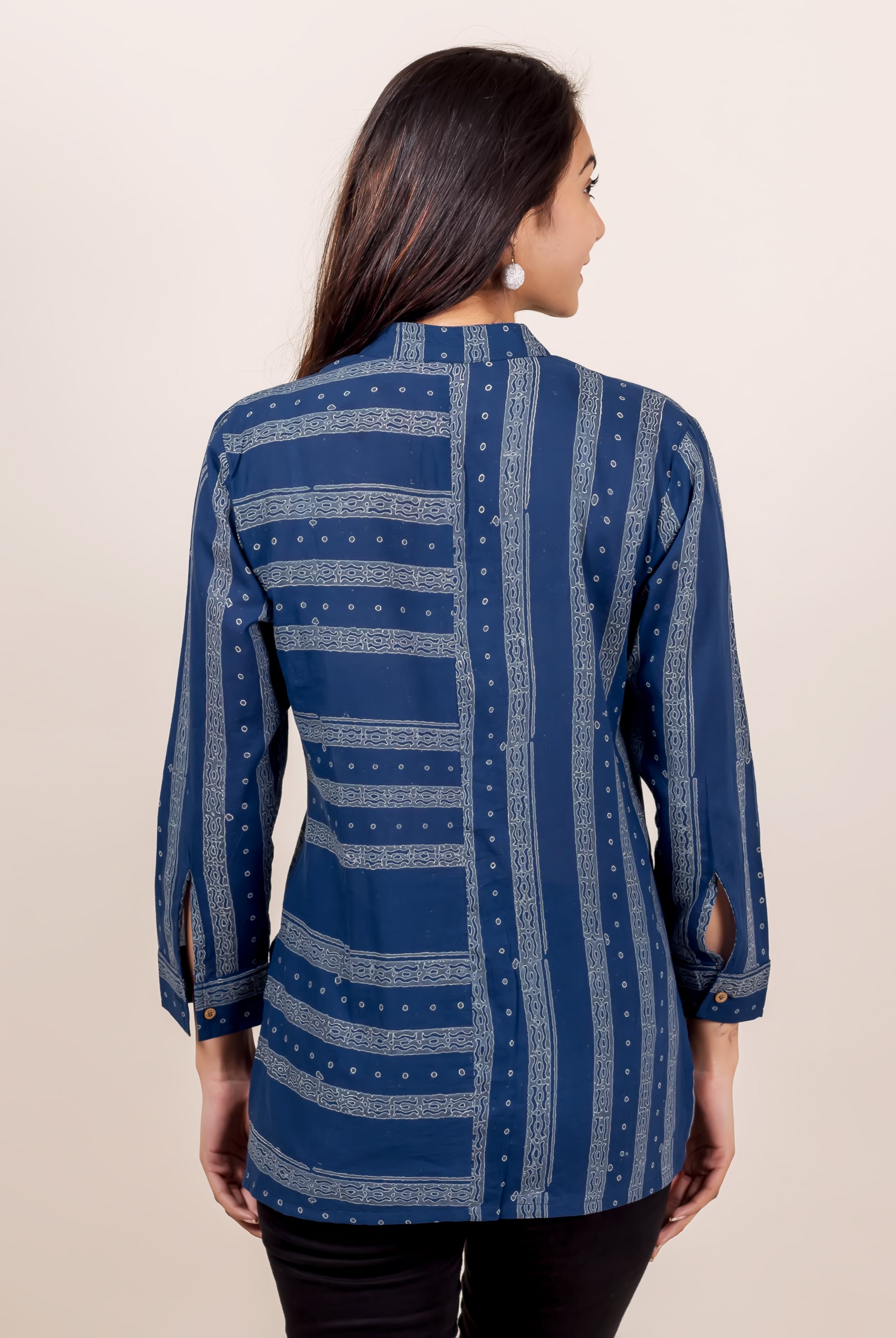 Back view of model in indigo shirt with varied block print patterns and sleeve slits.