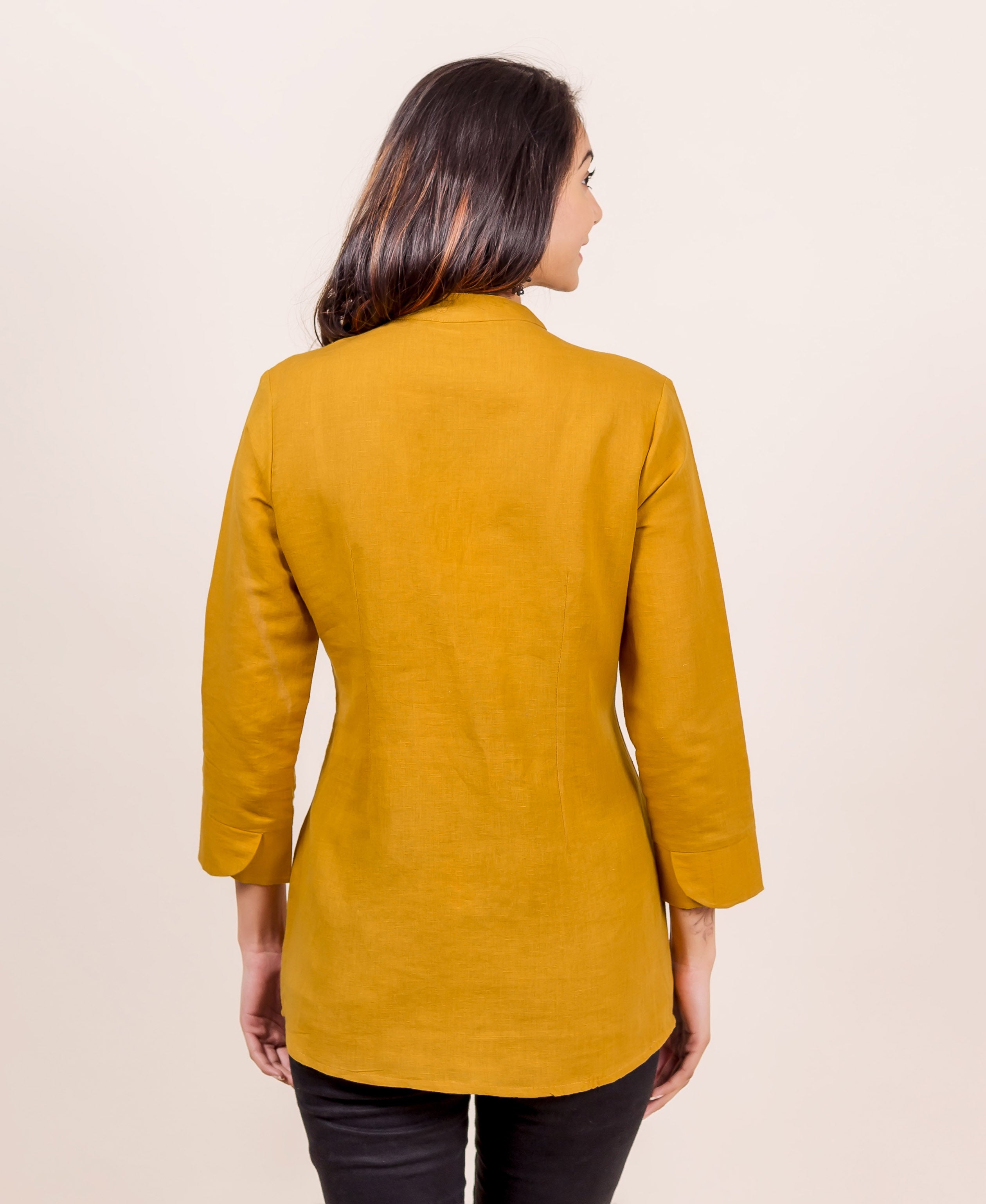 A model wearing a mustard linen mandarin collar top with a subtle block print.